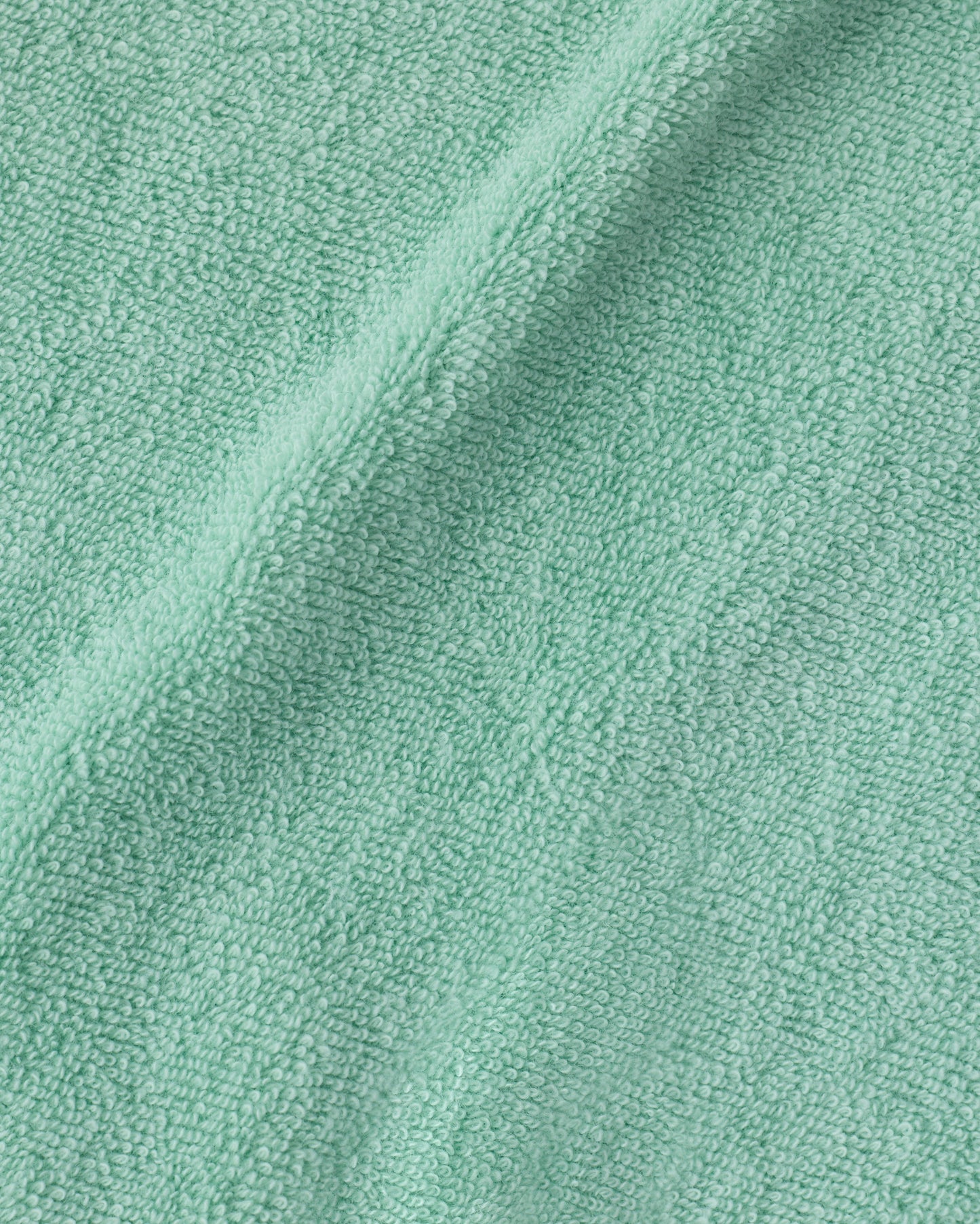 Close up of the soft material on the hooded towel of the Newborn Bath Set in Mint, including hooded towel, hair brush and bath mitt.