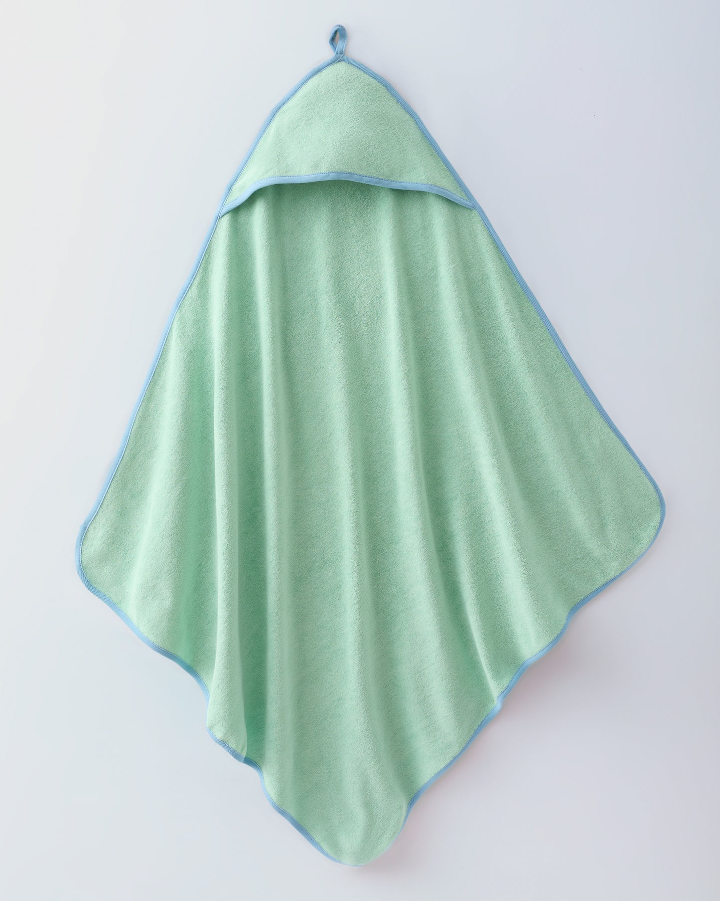 Hooded towel in the Newborn Bath Set in Mint, including hooded towel, hair brush and bath mitt, on a beige background.
