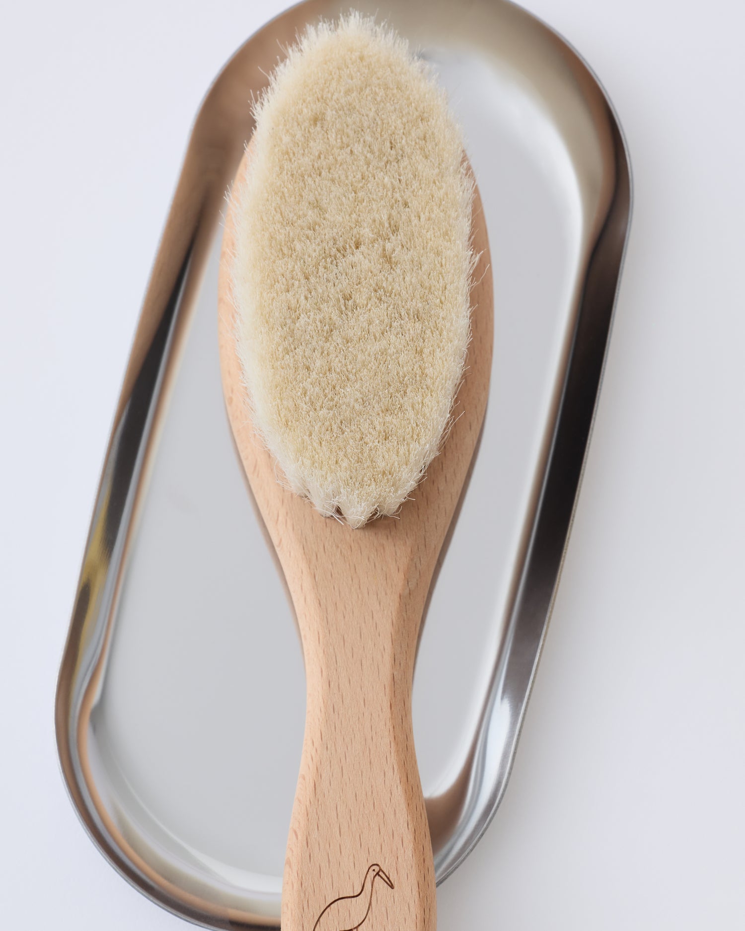 Natural wood hairbrush from the Newborn Bath Set in Mint, on a beige background.