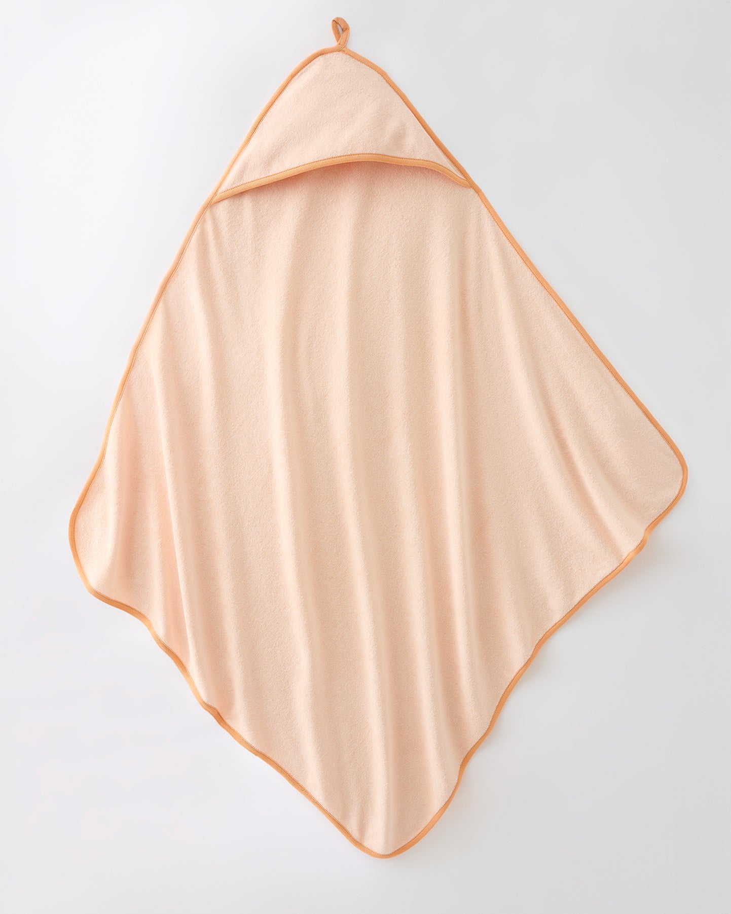 Hooded towel in the Newborn Bath Set in Peach Whip, on a beige background.