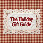 A square graphic with the text 'The Holiday Gift Guide' in red serif lettering on a white fabric-like panel with a scalloped lace border, set against a red and beige gingham check background.