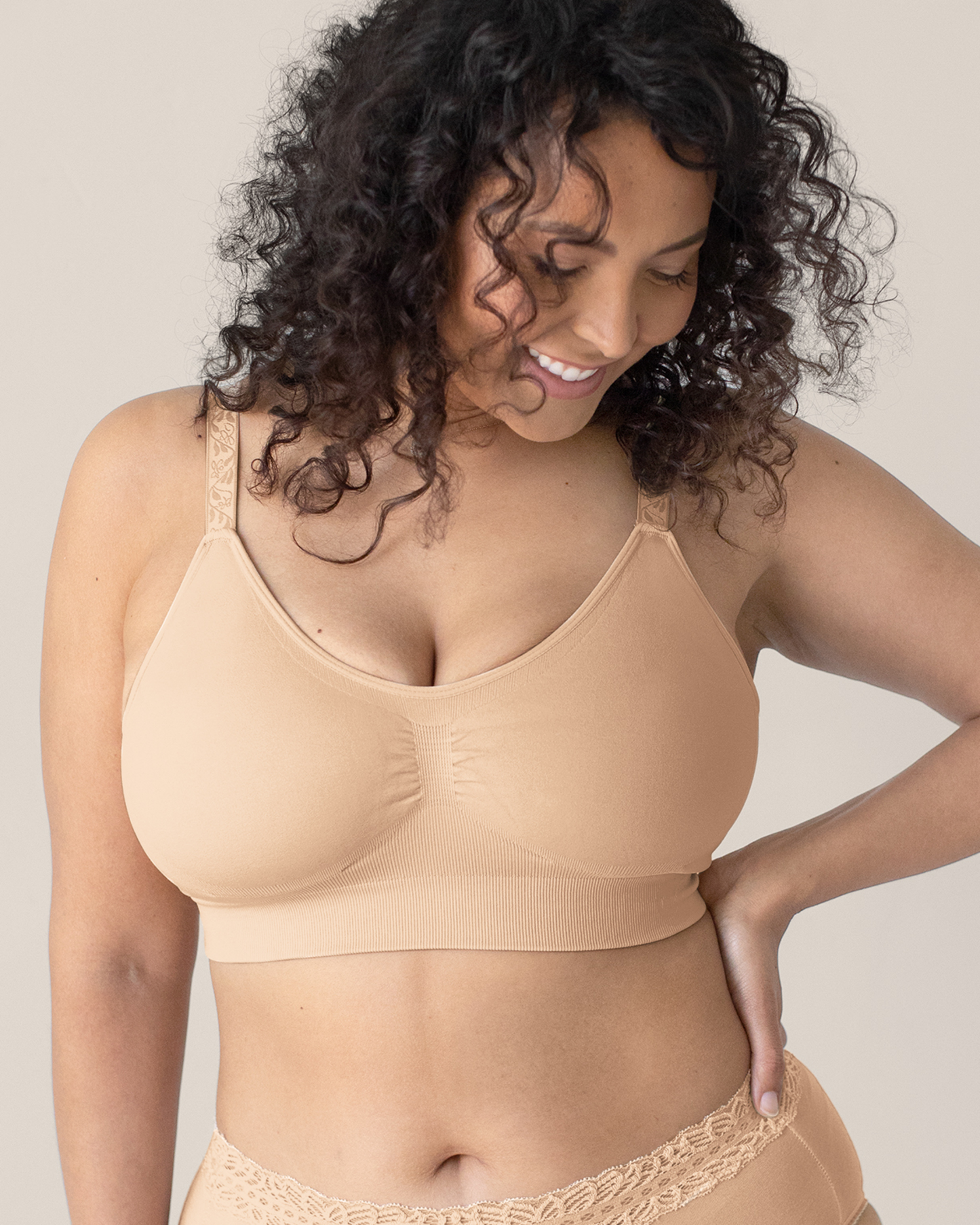 Woman wearing a beige bra against a neutral background@model_info:Sierra is wearing a Medium Busty.