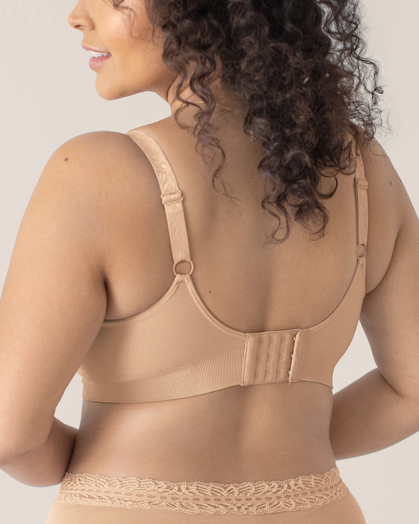 Woman wearing a beige bra against a neutral background