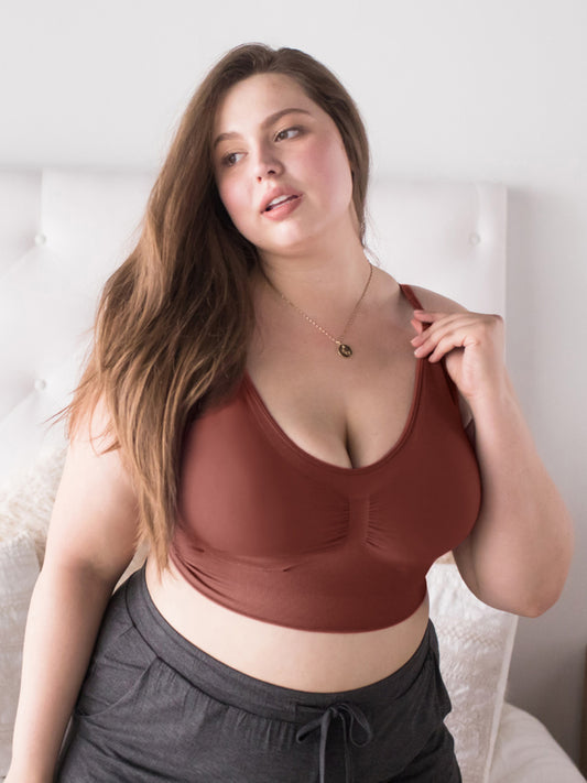 Model wearing the Nellie Sublime® Wireless Bra in with her hand on the strap. @model_info:Bailey is wearing an X-Large Busty.
