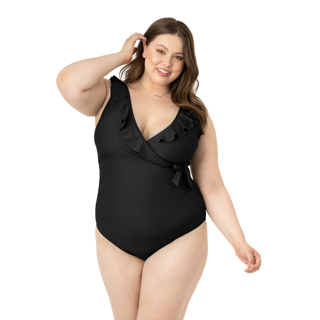Model tucking her hair behind her ear while wearing the Ruffle Wrap Maternity & Nursing One Piece Swimsuit in Black