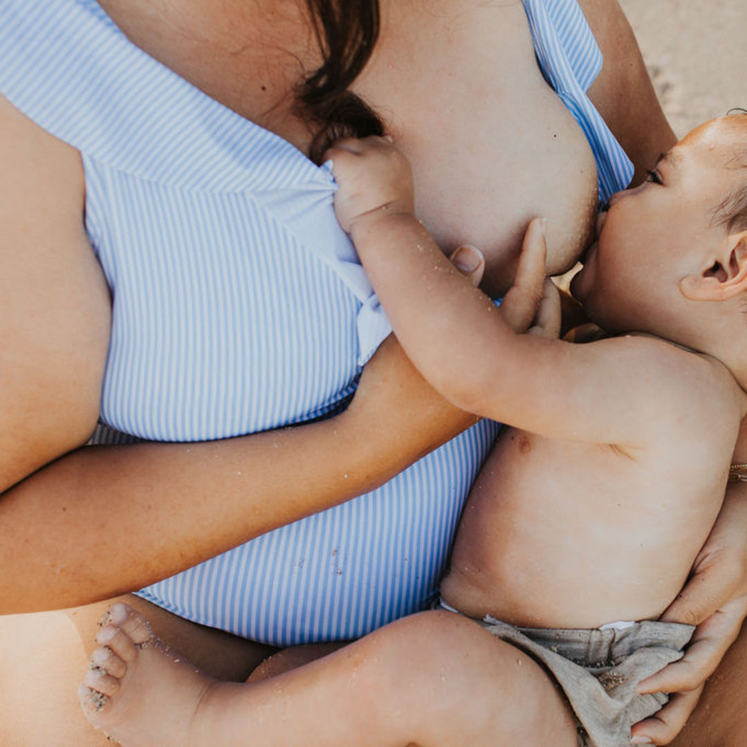 Model breastfeeding her baby through the Ruffle Wrap Maternity & Nursing One Piece Swimsuit in Coastal Stripe @model_info:Kyllie is 8 months pregnant and wearing an X-Large.