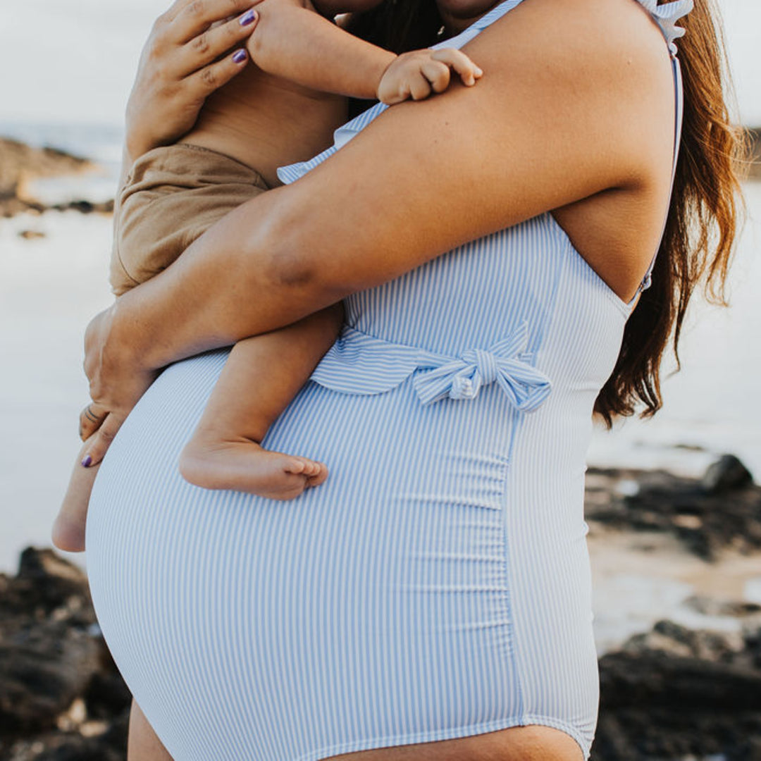 Model wearing the Ruffle Wrap Maternity & Nursing One Piece Swimsuit in Coastal Stripe