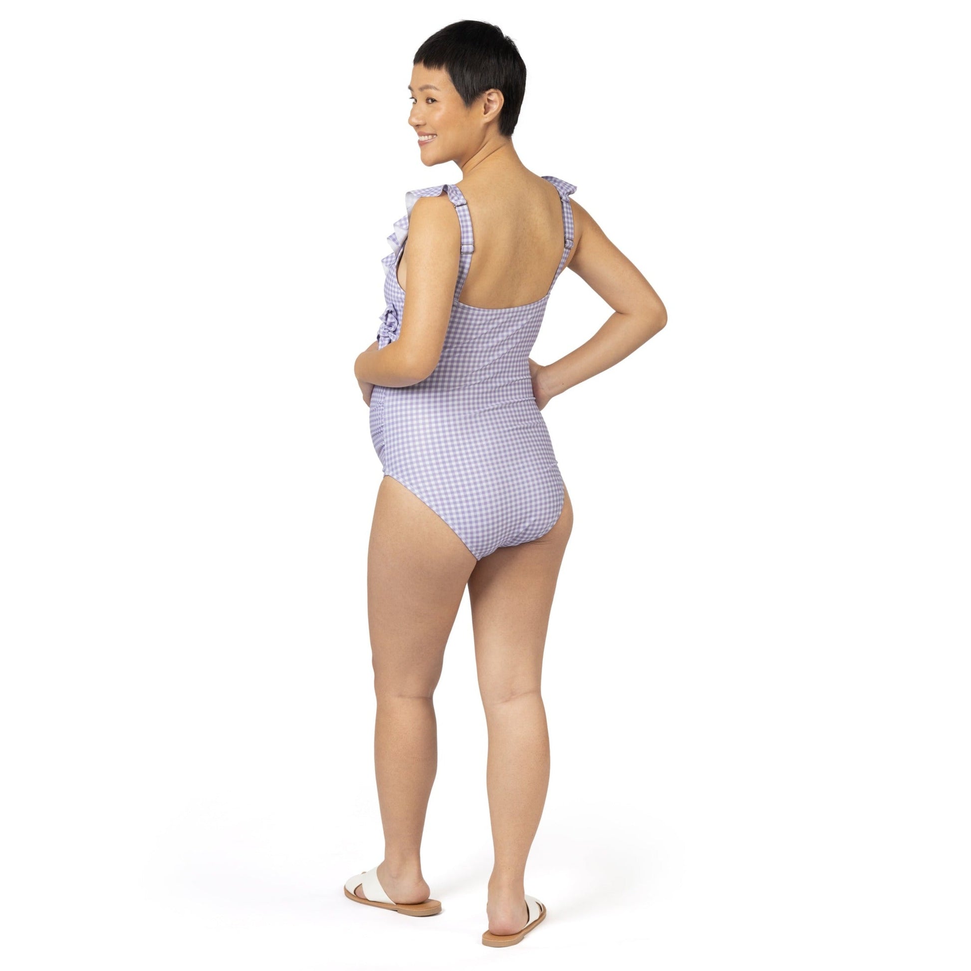 Back view of a pregnant model wearing the Ruffle Wrap Maternity & Nursing One Piece Swimsuit in Lavender Gingham