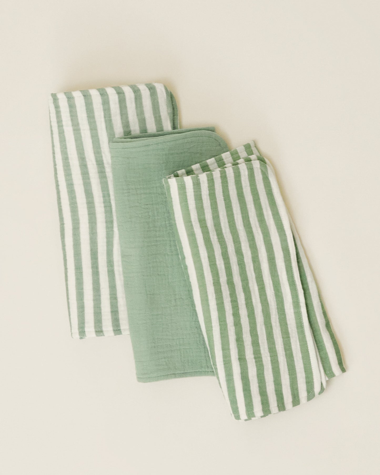 A set of Organic Muslin Burp Cloth in Sage Stripe print, folded neatly and displayed on a plain surface.