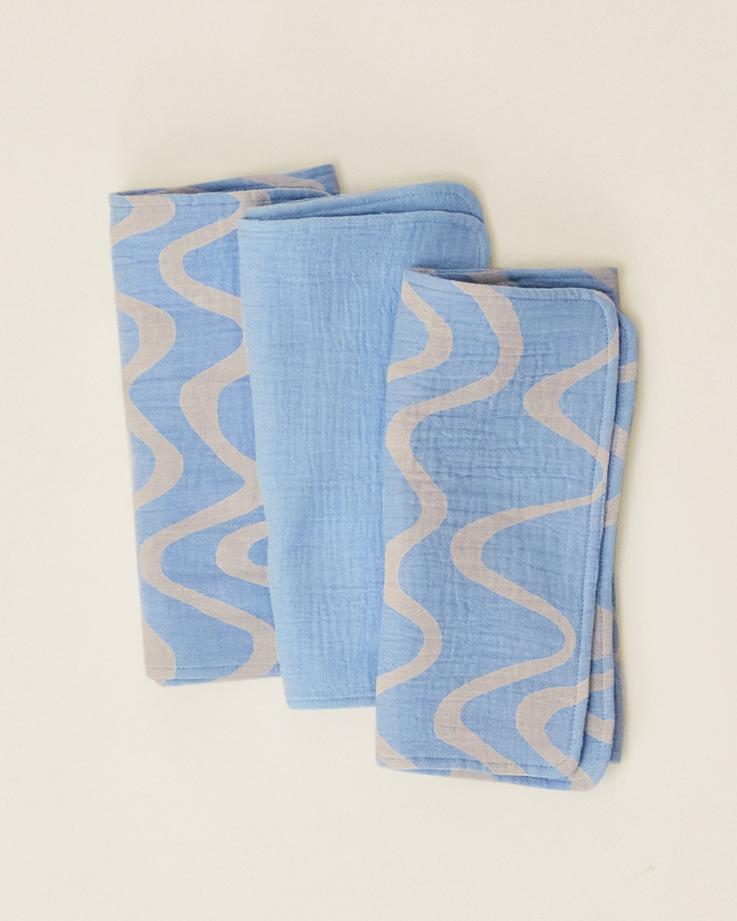 A set of Organic Muslin Burp Cloth in the Blue Waves print, folded neatly and displayed on a plain surface.