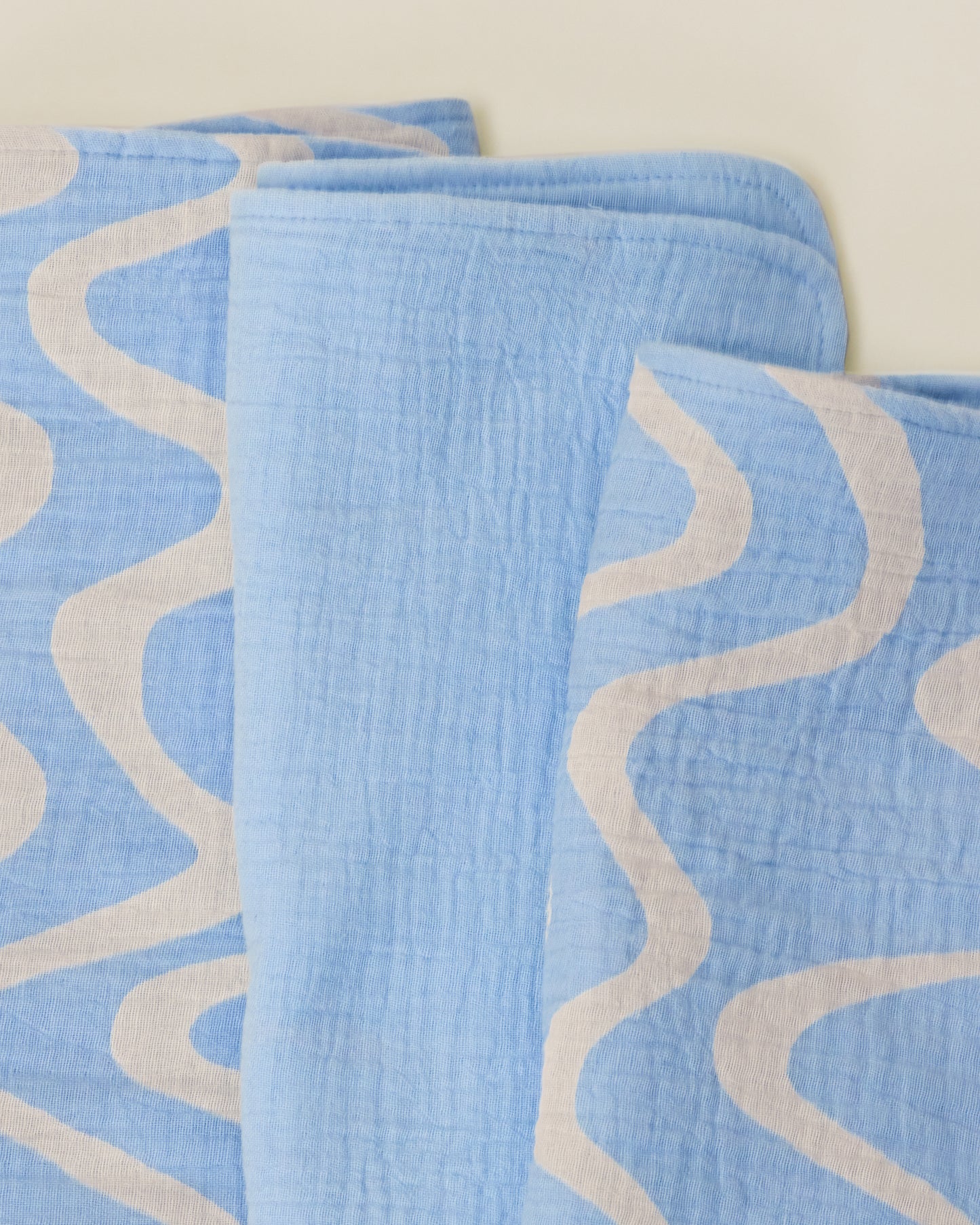Close up of the set Organic Muslin Burp Cloth in Blue Waves print.