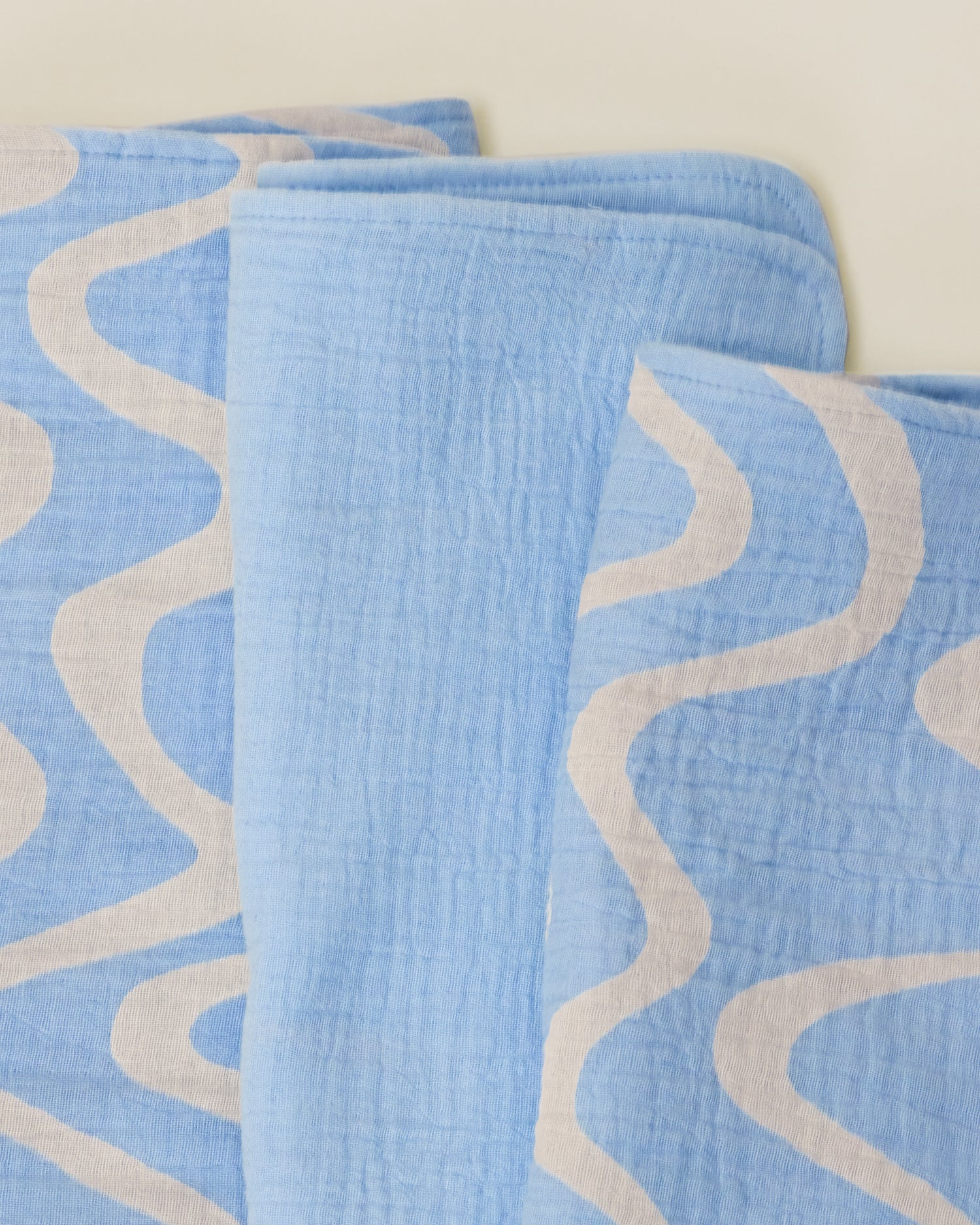 Close up of the set Organic Muslin Burp Cloth in Blue Waves print.
