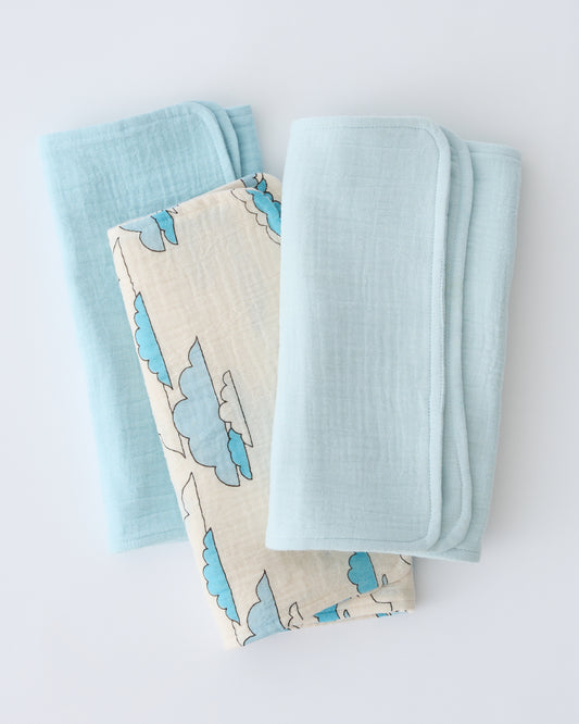 Organic Muslin Burp Cloth (Three-Pack) in Ivory Clouds, folded and stacked, on a beige background.