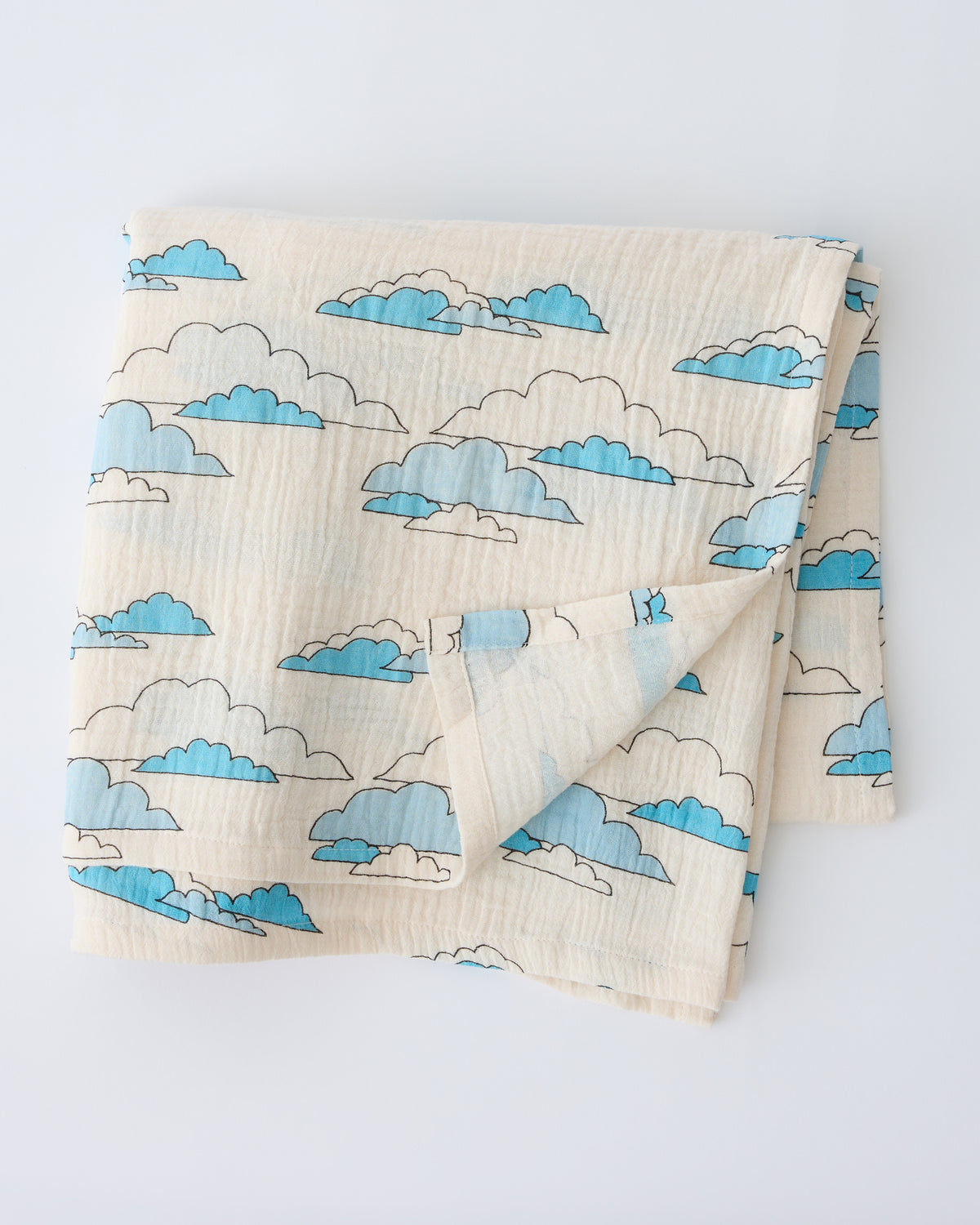 Organic Muslin Swaddle in Ivory Clouds, folded with corner flipped back to show reverse side, on a beige background.