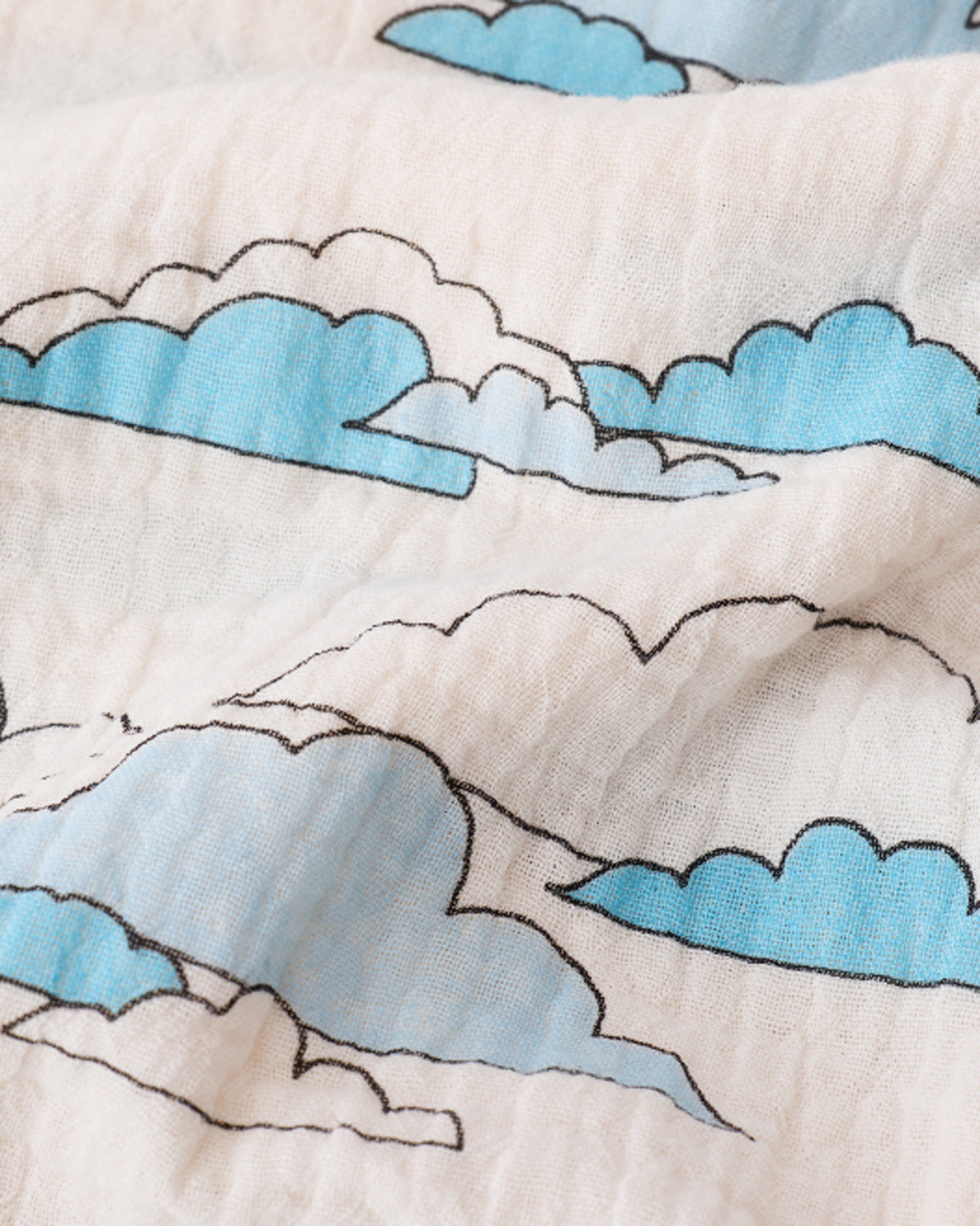 Close up of the Organic Muslin Swaddle in Ivory Clouds pattern. 