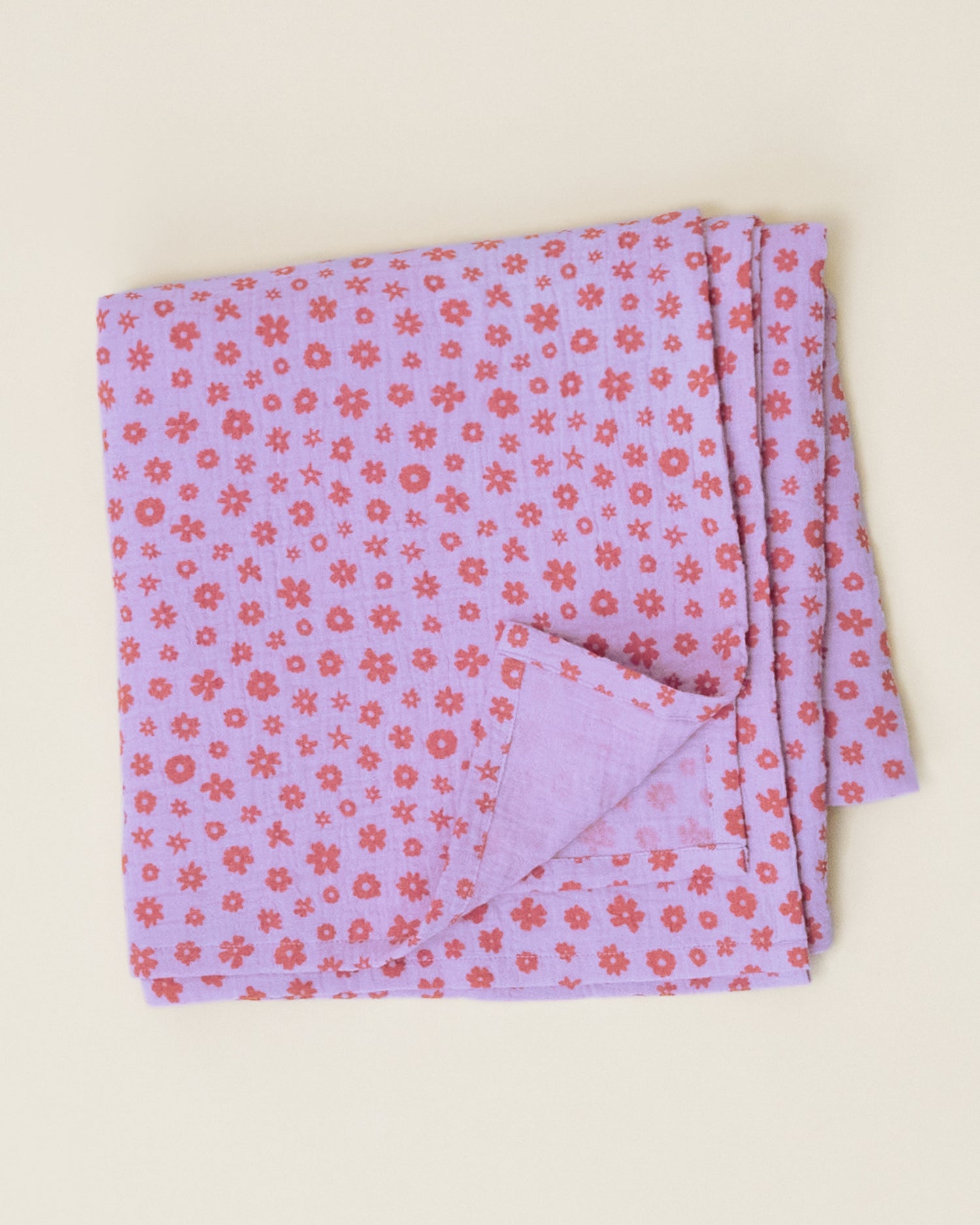 The Organic Muslin Swaddle in the Lavender Cosmos print, folded neatly and displayed on a plain surface.