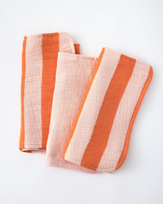 Organic Muslin Burp Cloth (Three-Pack) in Pink Wide Stripe on a beige background.