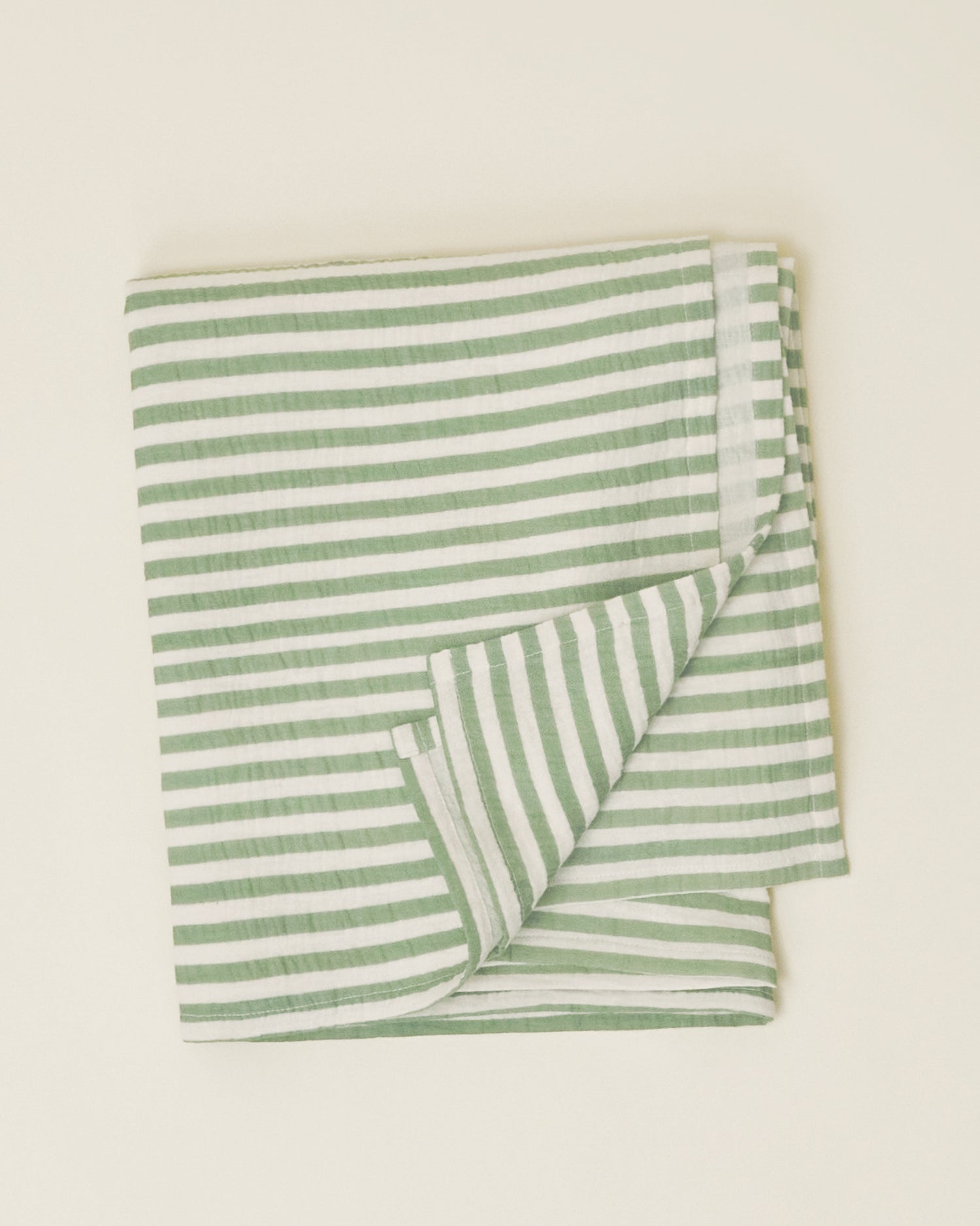 The Organic Muslin Swaddle in the Sage Stripe print, folded neatly and displayed on a plain surface.