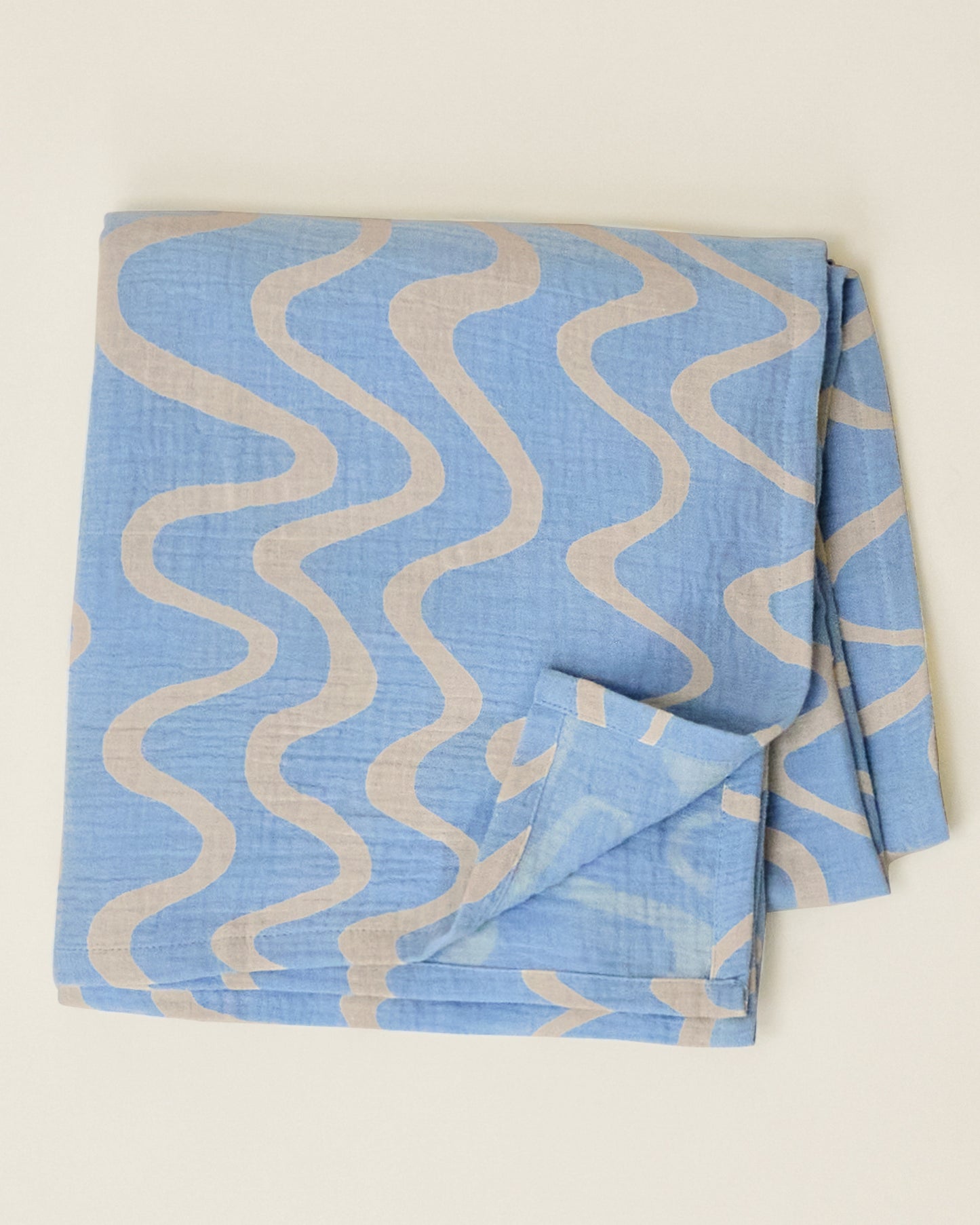 The Organic Muslin Swaddle in the Blue Waves print, folded neatly and displayed on a plain surface.