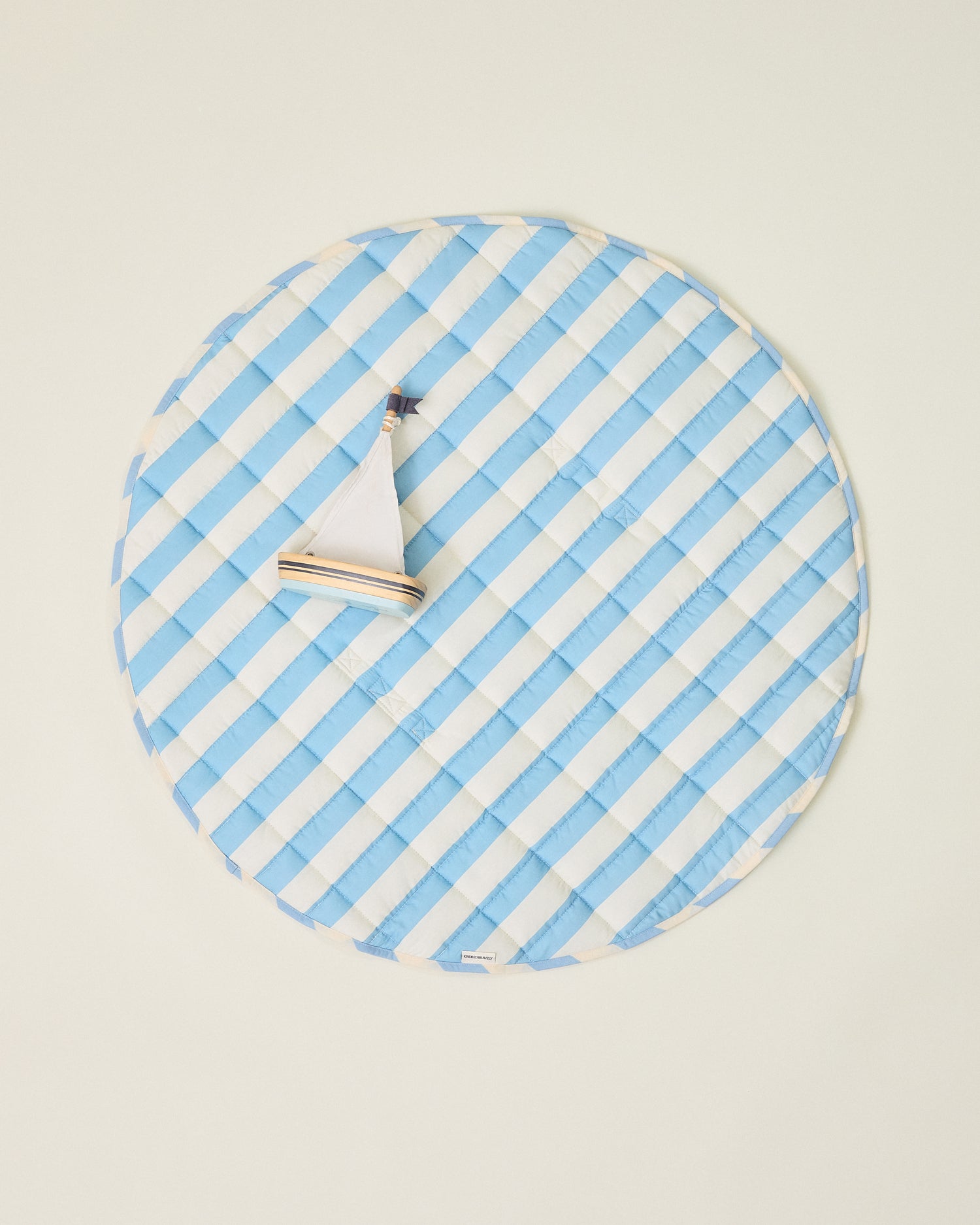 Inside/Outside Play Mat in Blue Wide Stripe with blue and white stripes with toy sailboat on a beige background