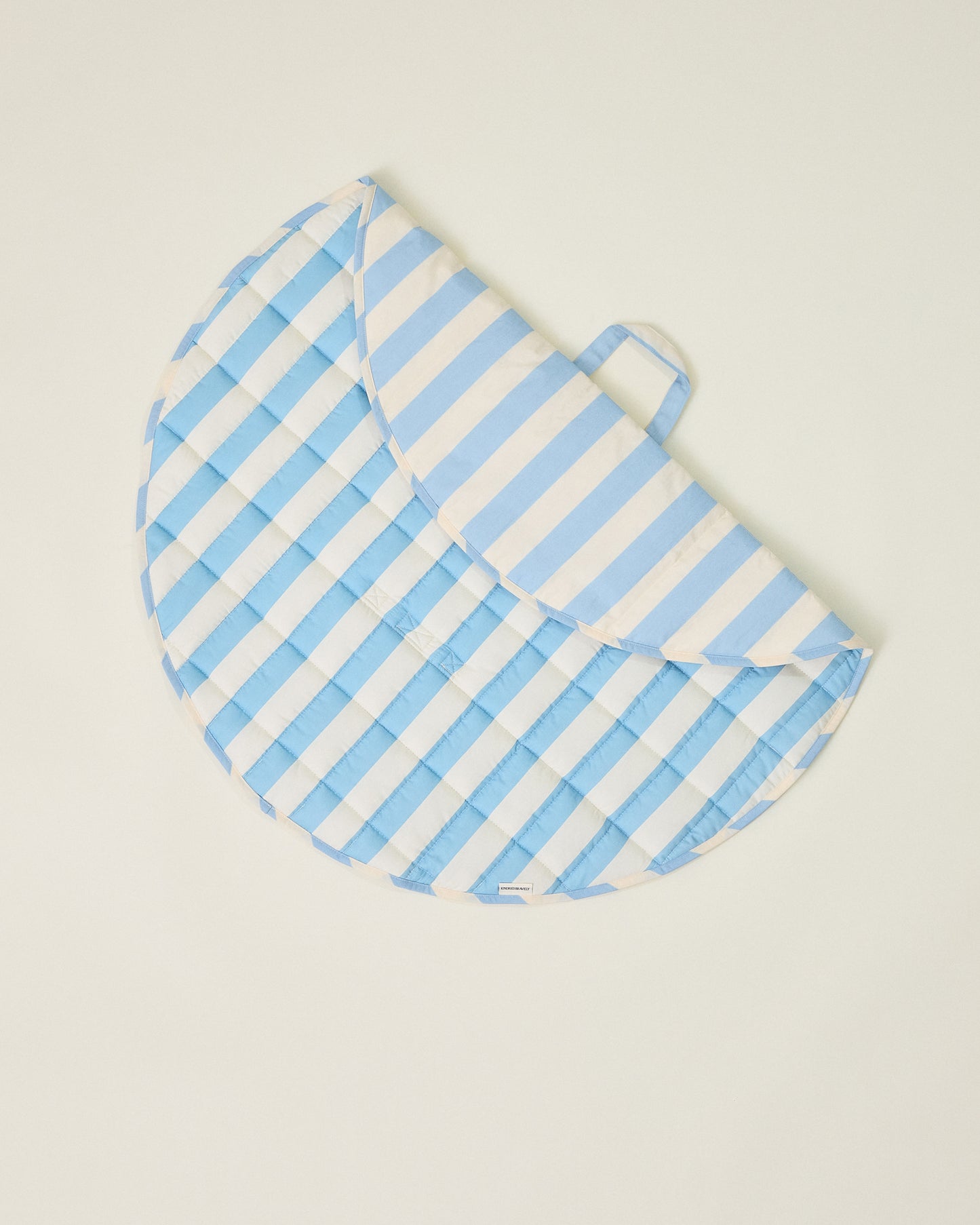 Inside/Outside Play Mat in Blue Wide Stripe, partly folded and displaying two different patterns on a beige background