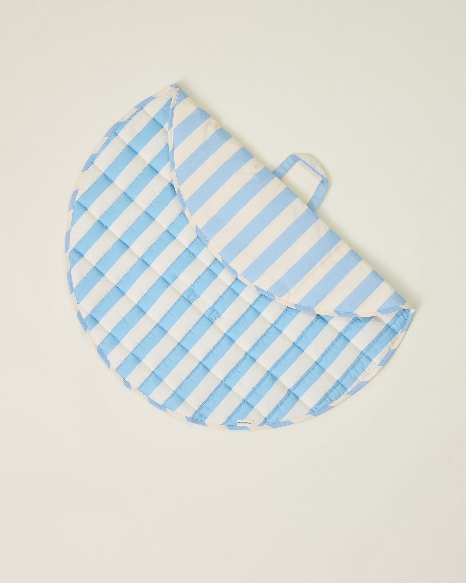 Inside/Outside Play Mat in Blue Wide Stripe, partly folded and displaying two different patterns on a beige background