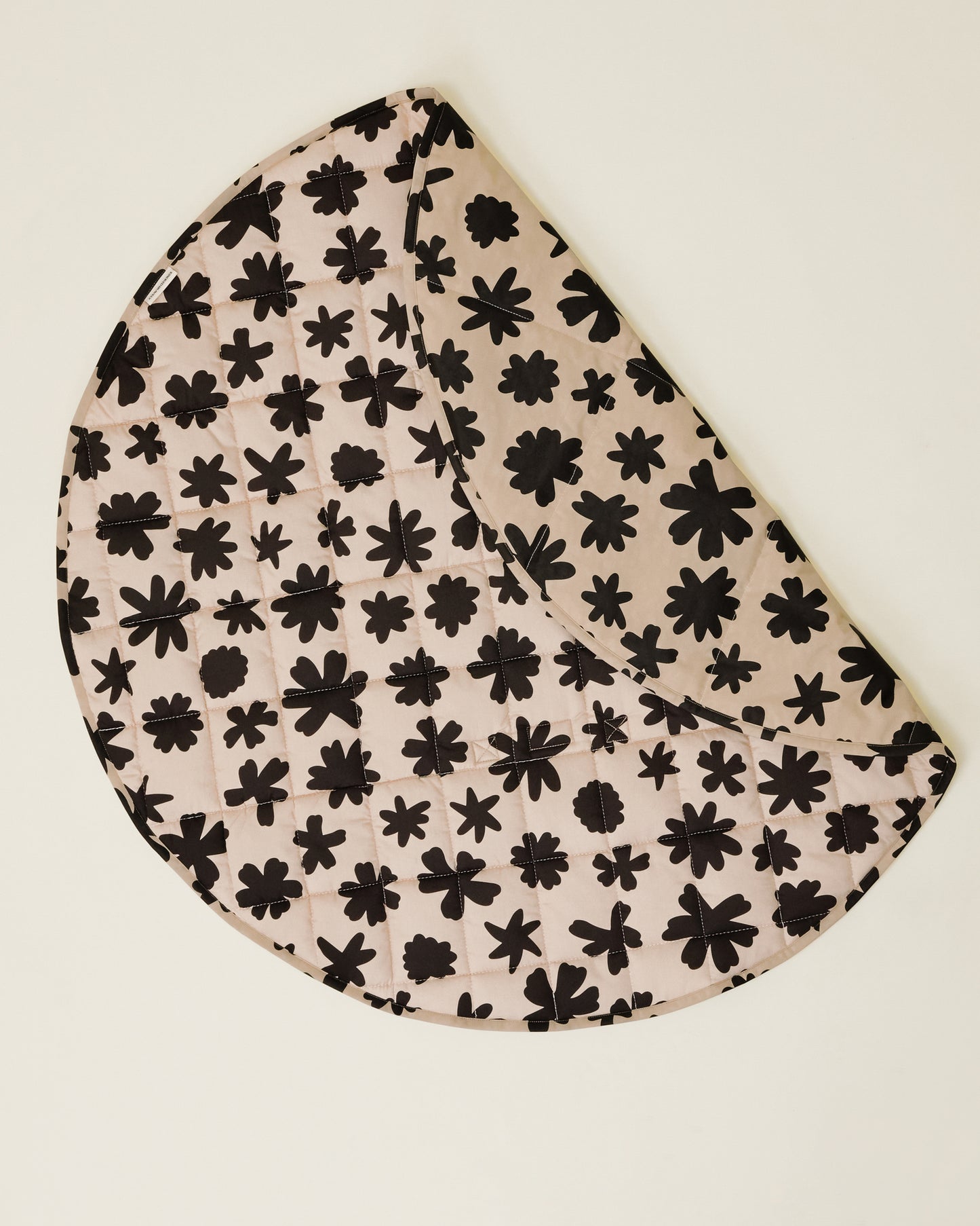 The Inside/Outside Play Mat in Cream Chamomiles print, partly folded to display the two sides of the mat.