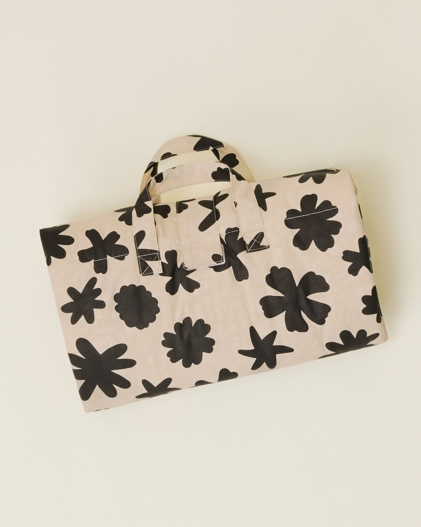 The Inside/Outside Play Mat in Cream Chamomiles print, folded into a neat rectangle with a handle.