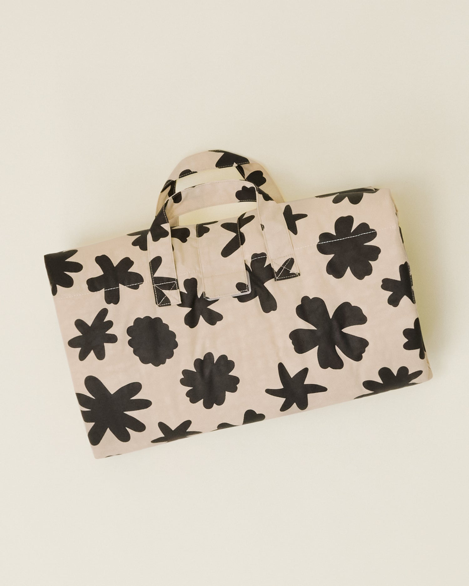 The Inside/Outside Play Mat in Cream Chamomiles print, folded into a neat rectangle with a handle.