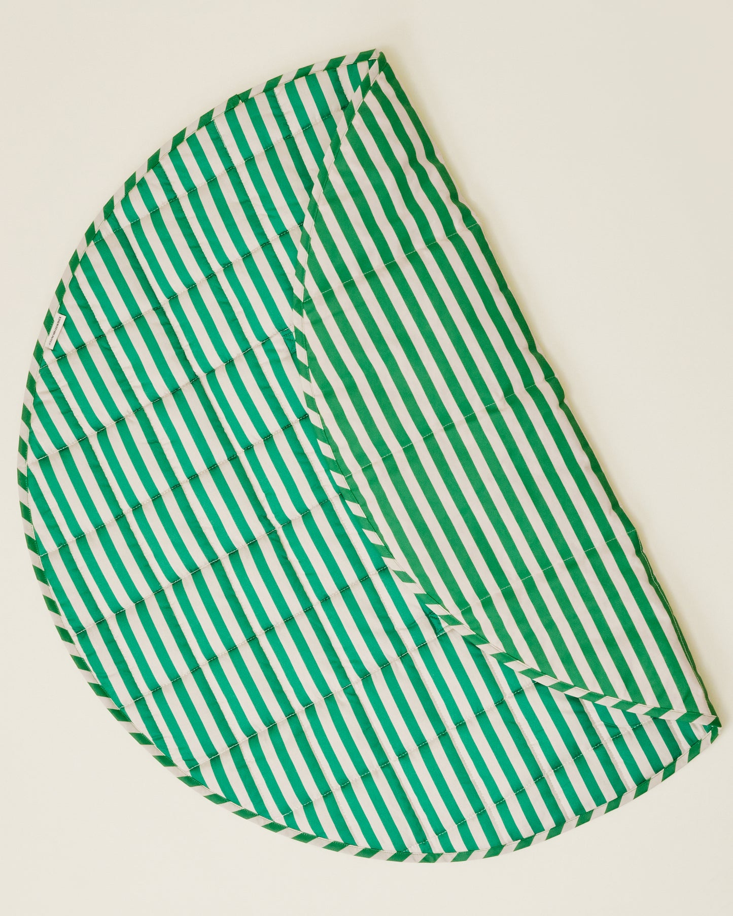 The Inside/Outside Play Mat in Green Stripe print, partly folded to display the two sides.