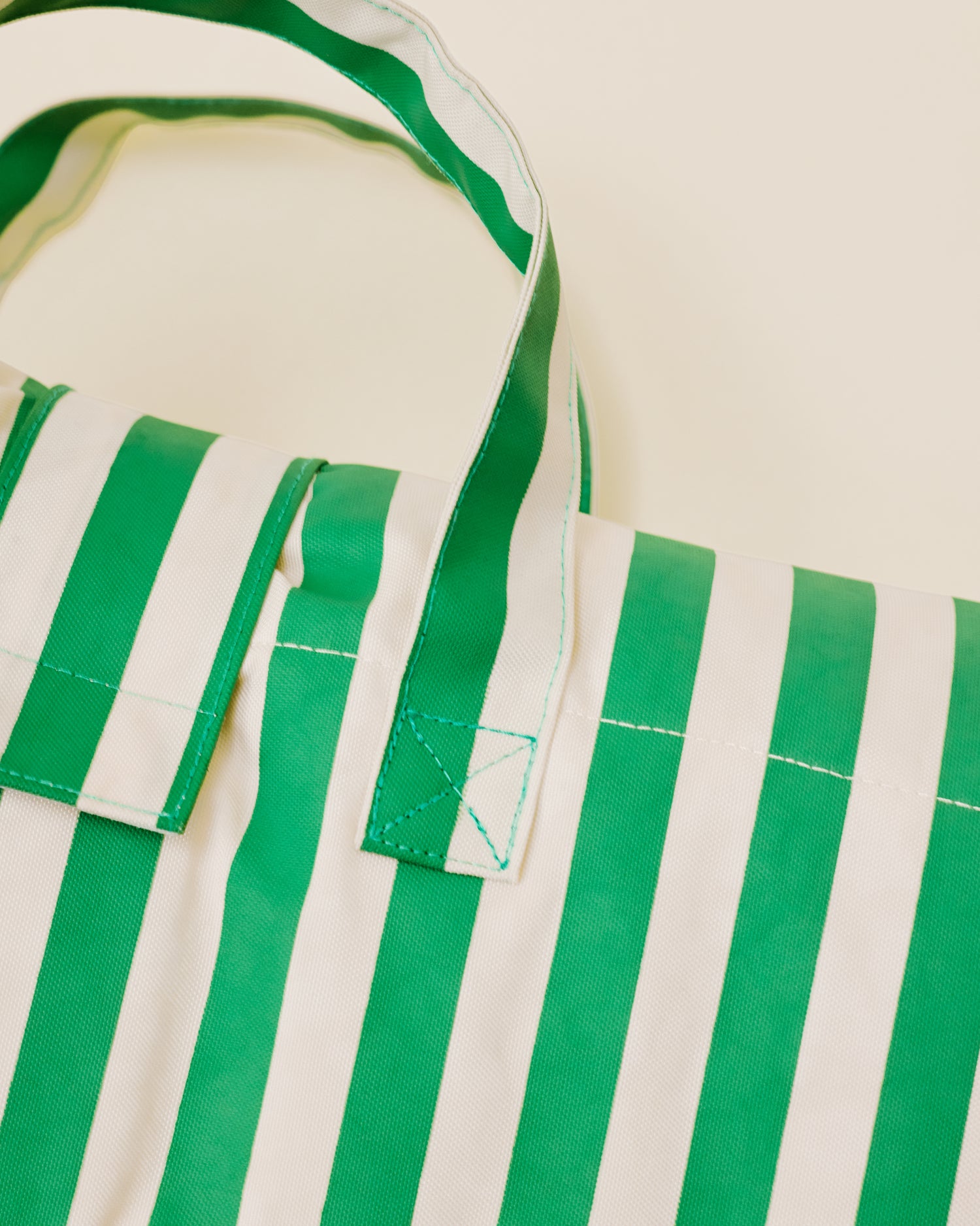 Close up of the Inside/Outside Play Mat in Green Stripe print, showing the detail of the inbuilt handle.