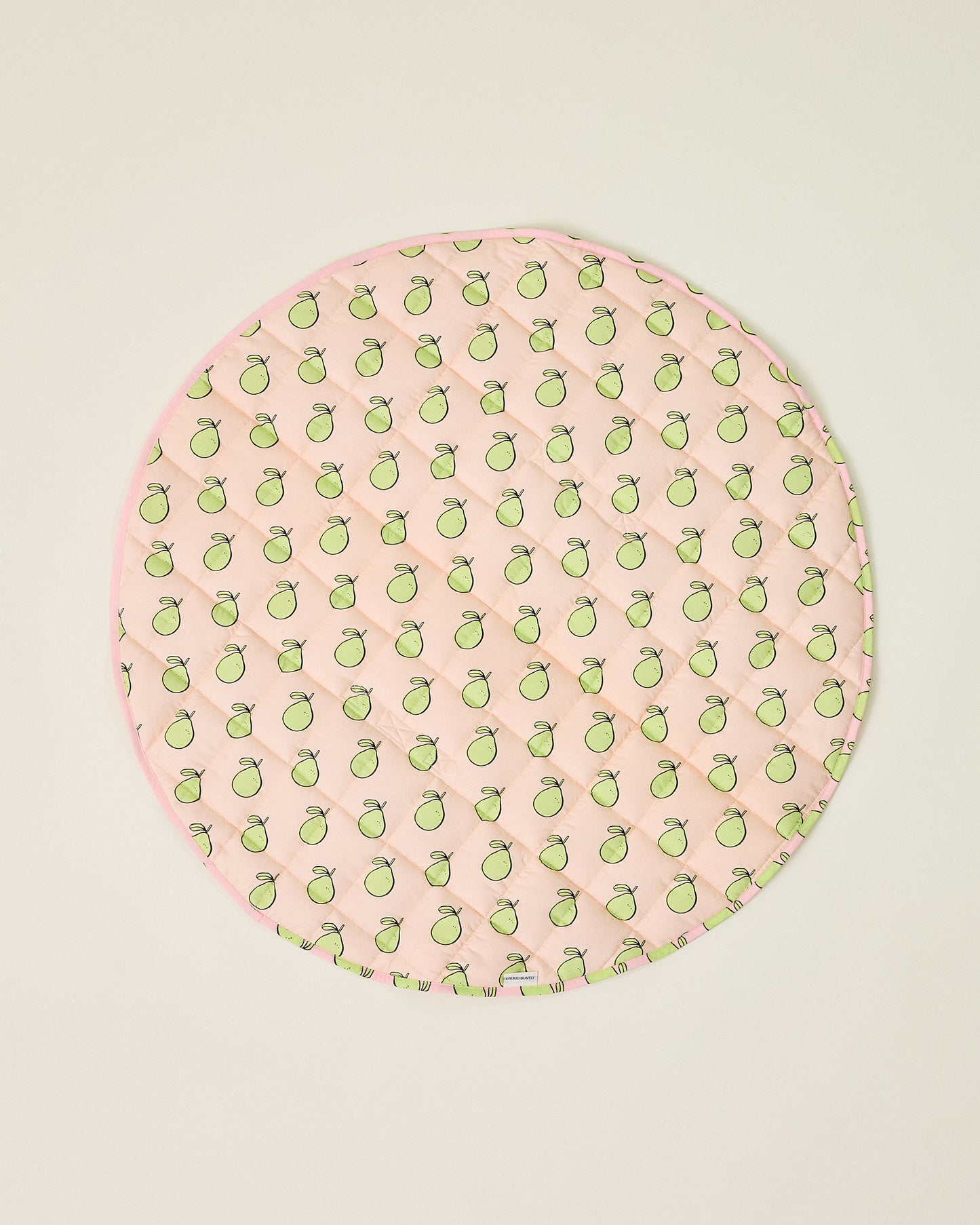 Round pink play mat with green pomelo pattern on a beige background