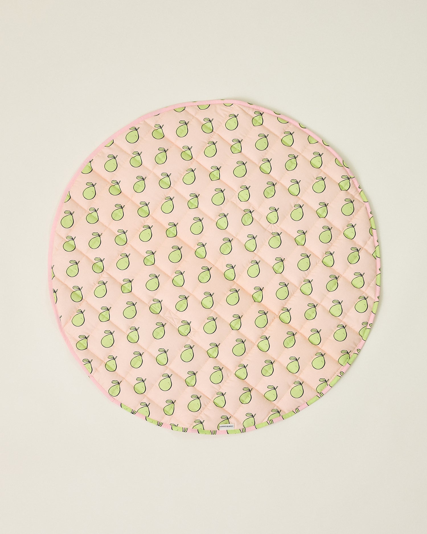 Round pink play mat with green pomelo pattern on a beige background