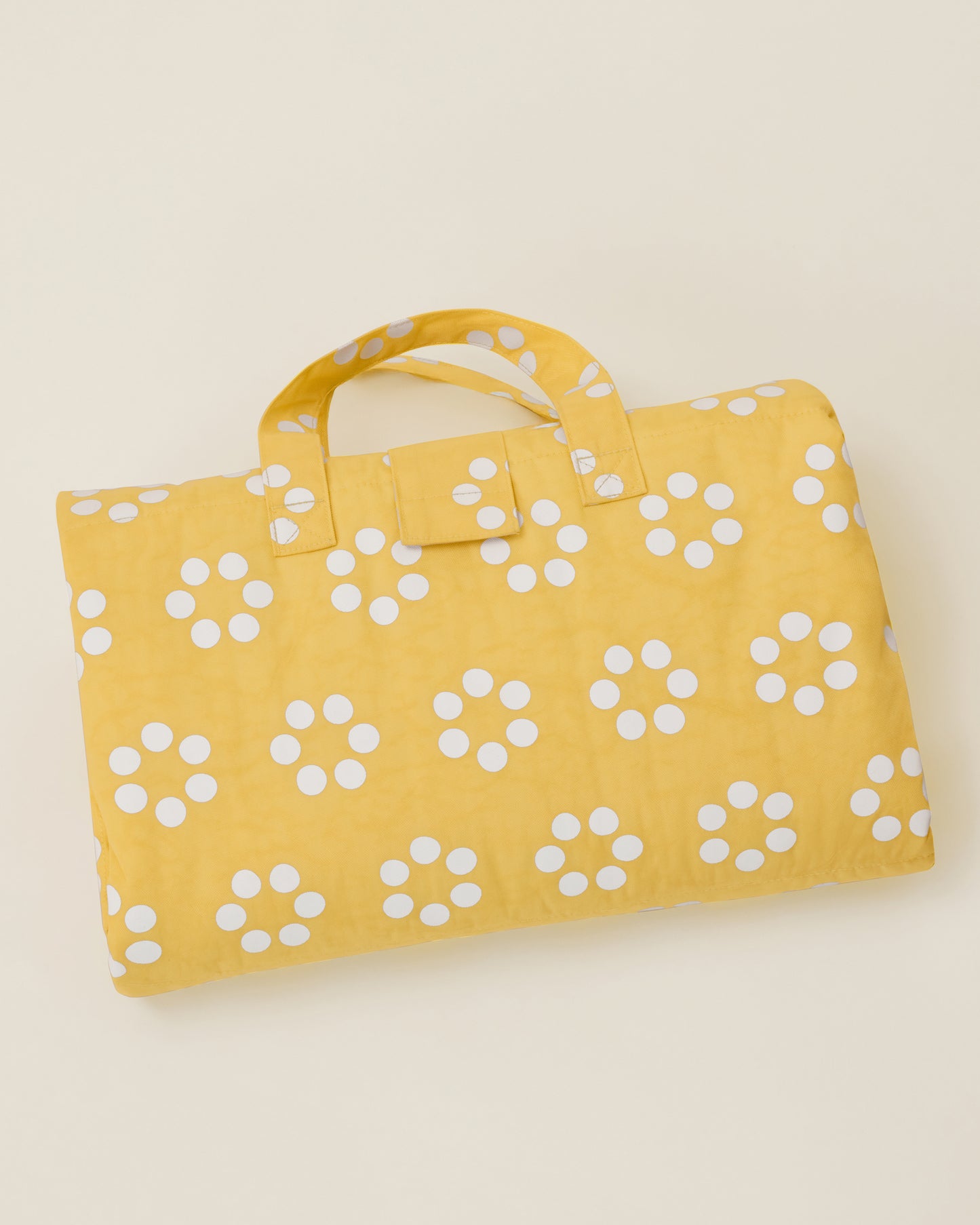 The Inside/Outside Play Mat in Sunshine Dots print, folded into a neat rectangle with a handle.