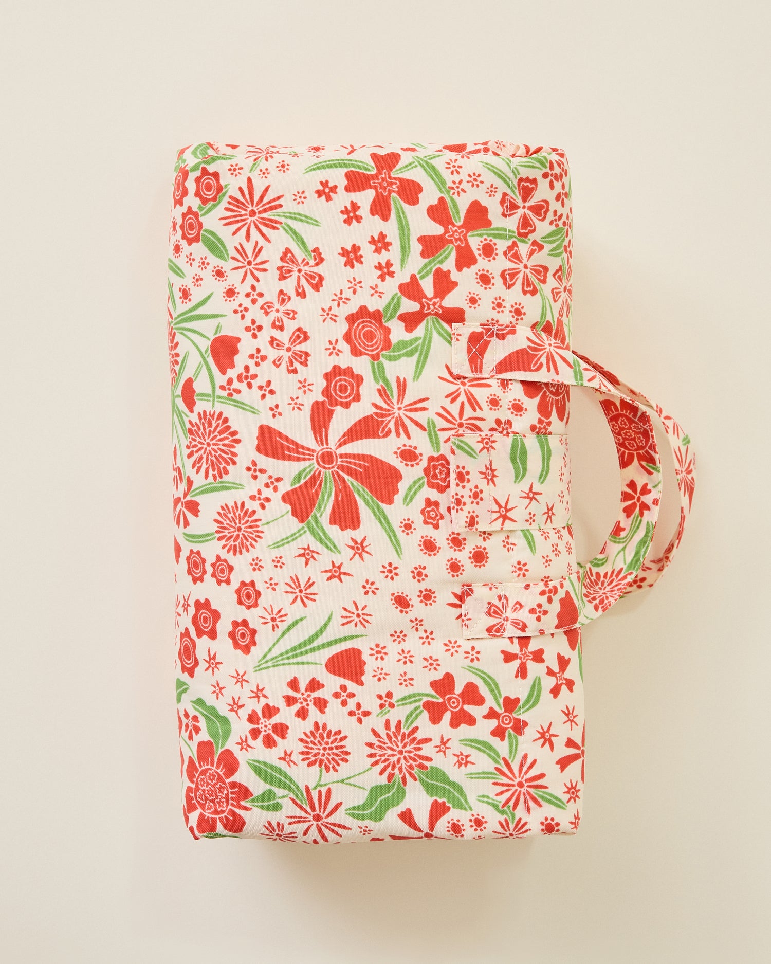 The Inside/Outside Play Mat in Superbloom print, folded into a neat rectangle with a handle, on a beige background