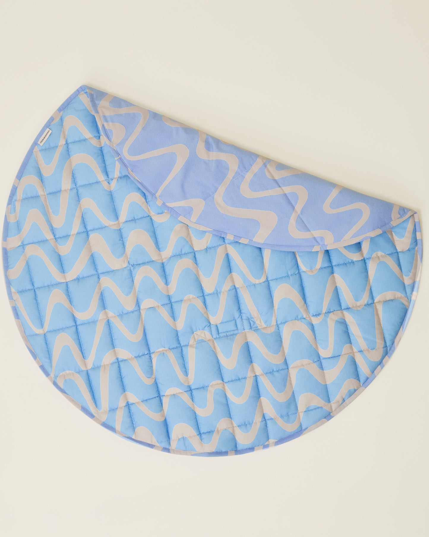 The Inside/Outside Play Mat in Blue Waves print, partly folded and displaying two different patterns.