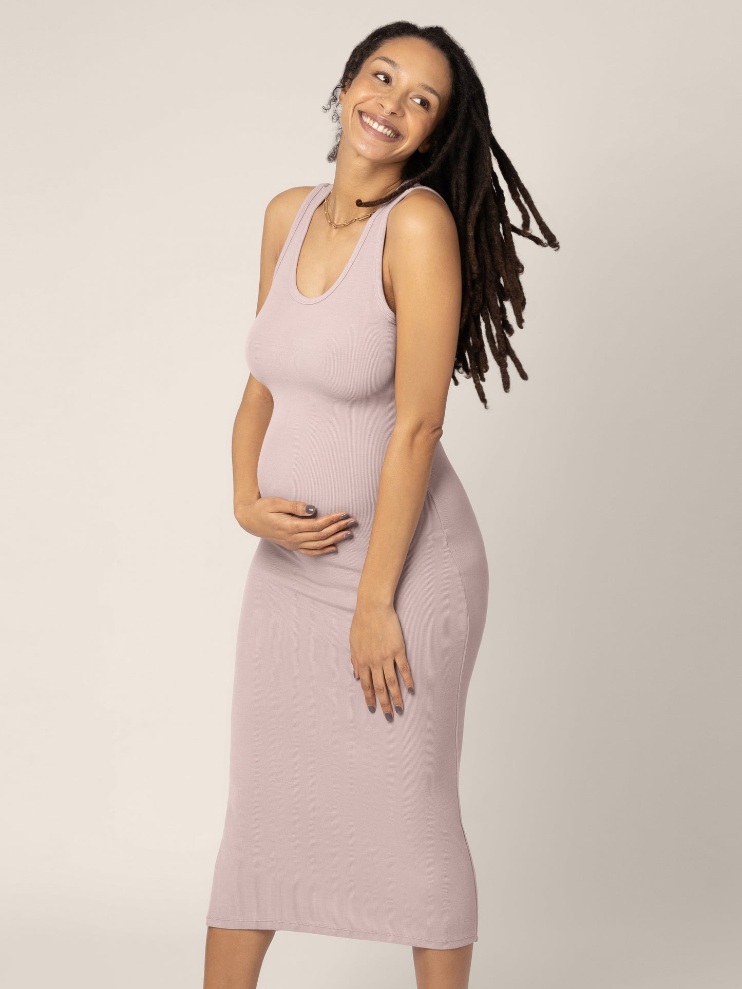 Model wearing the Olivia Ribbed Bamboo 2 in 1 Maternity & Nursing Dress in Lilac stone with her hand on her belly. @model_info:Chrissy is 5'11" and wearing a Medium.