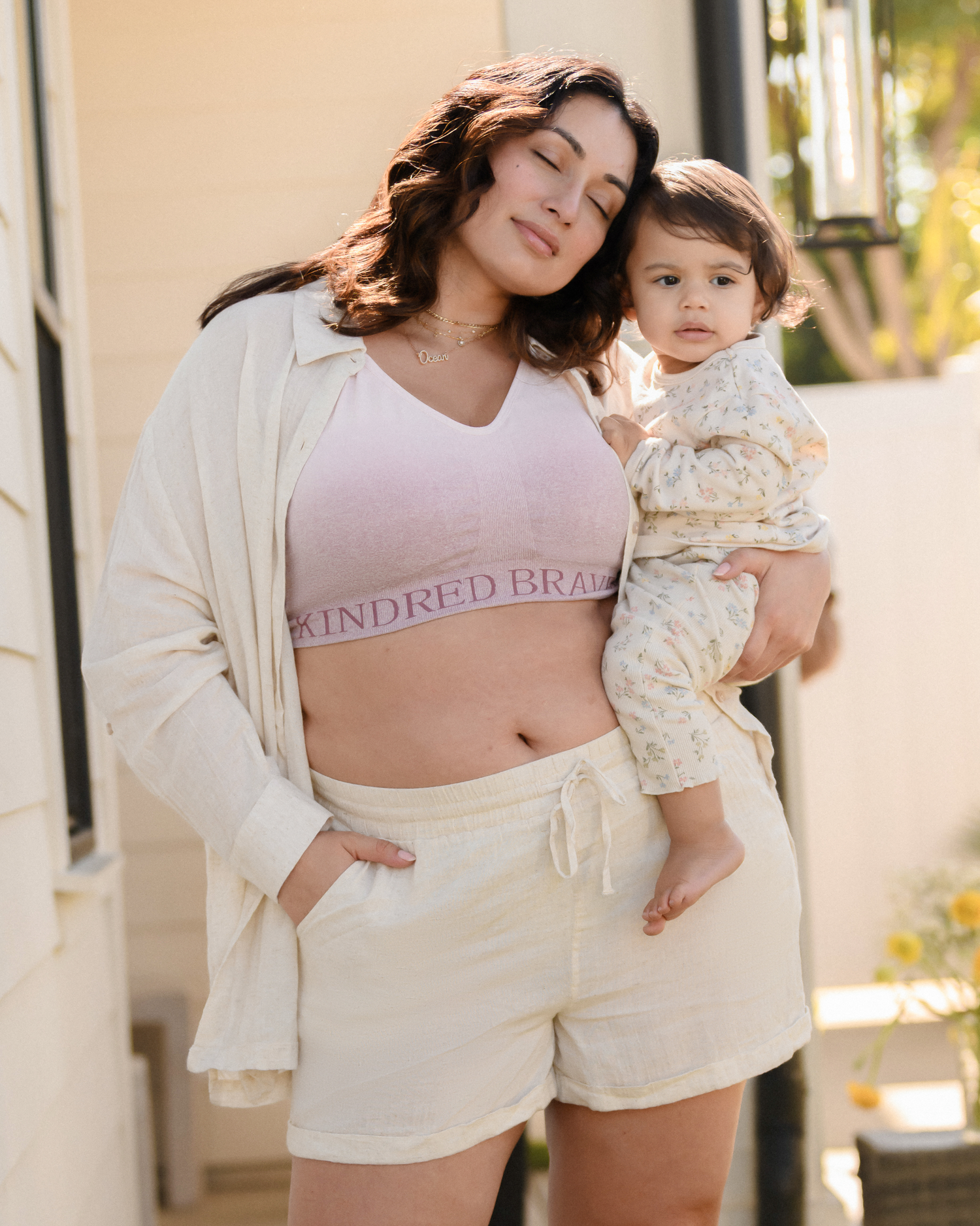 Model holding her baby and enjoying the fresh air while wearing the Sublime® Hands-Free Pumping & Nursing Sports Bra in Ombre Purple @model_info:Connie wearing an X-Large Busty.