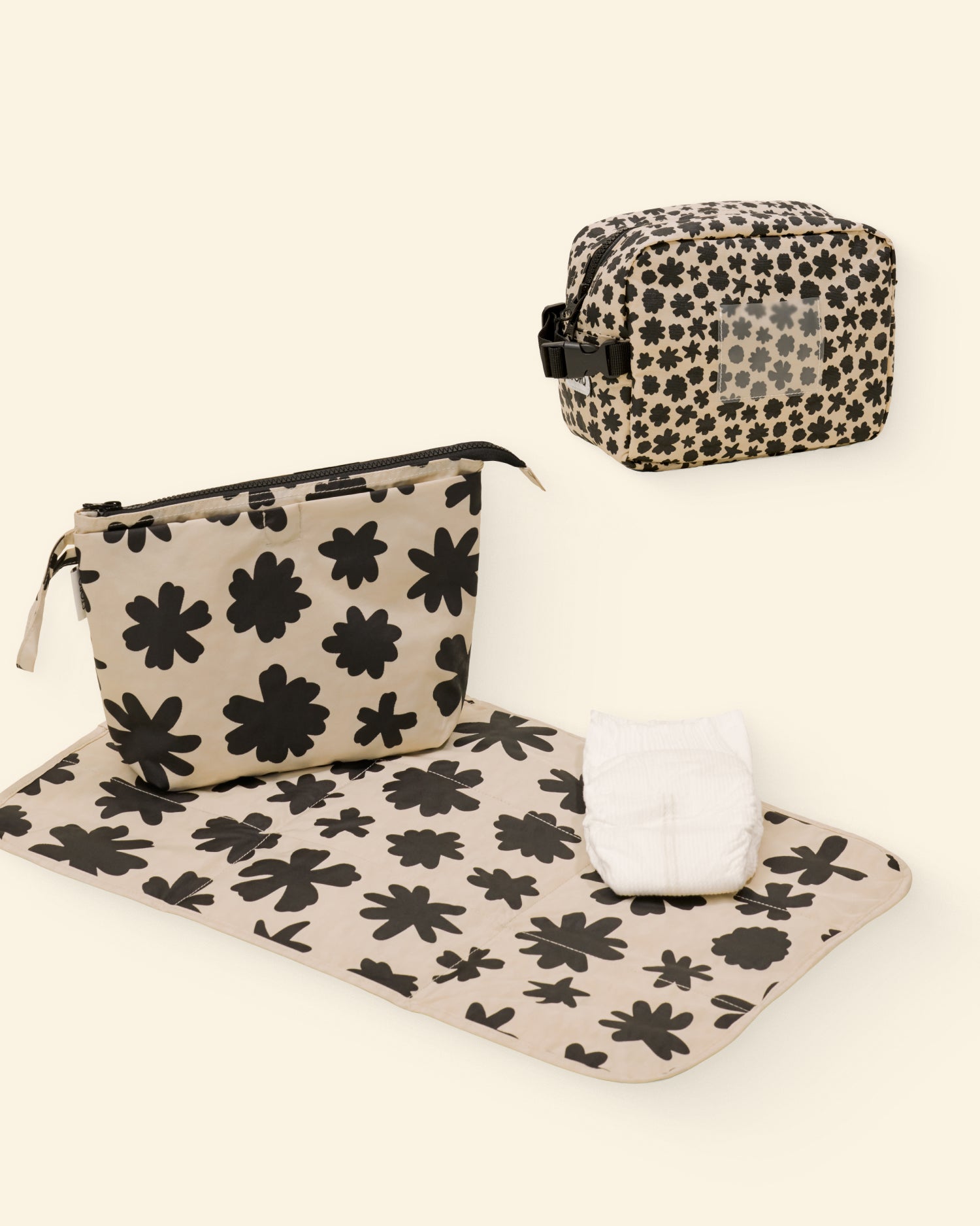 Set of black and beige floral-patterned pouches and mat on a light background