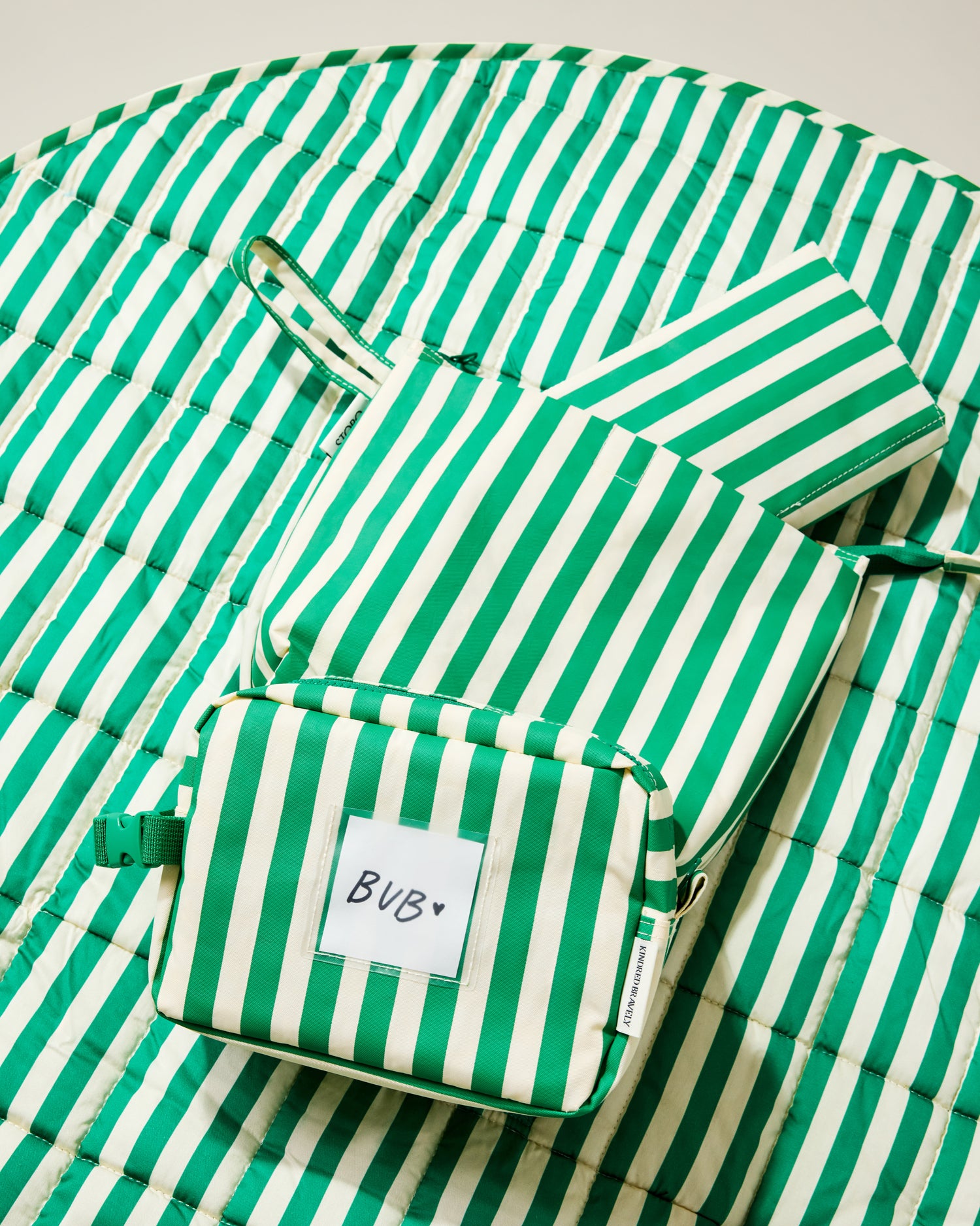 Set of green and white striped pouches and a play mat on a light background