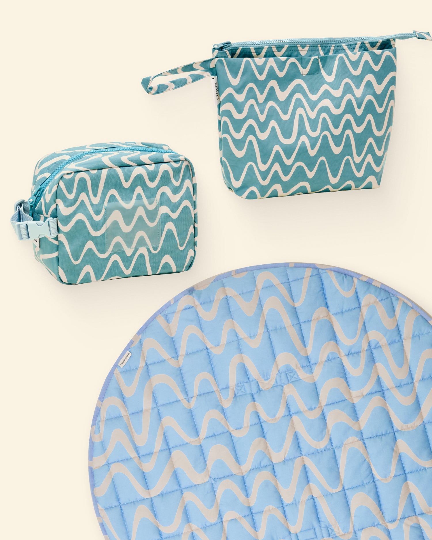 Set of blue and white wave patterned pouches and a play mat on a light background