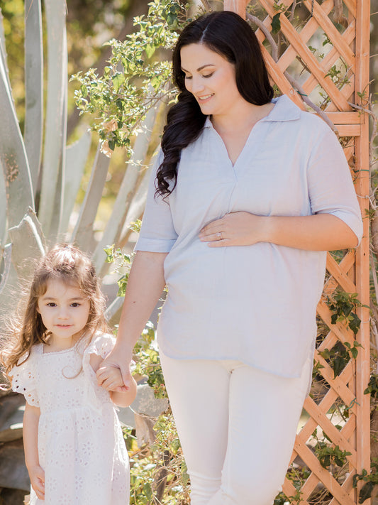 Model wearing the Oversized Nursing & Maternity Collared Top walking with her daughter. @model_info:Audrey is wearing a Medium.