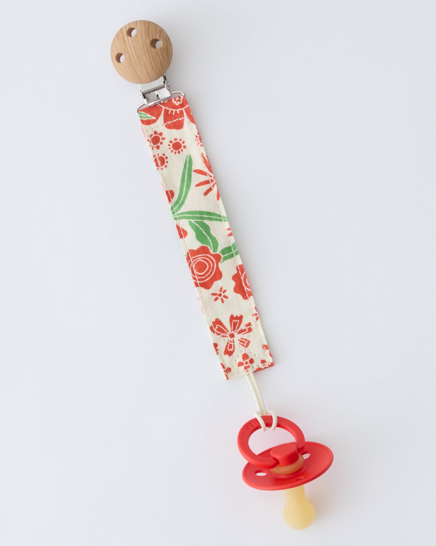 Pacifier Clip Two-Pack in Superbloom, attached to pacifier, on a beige background.