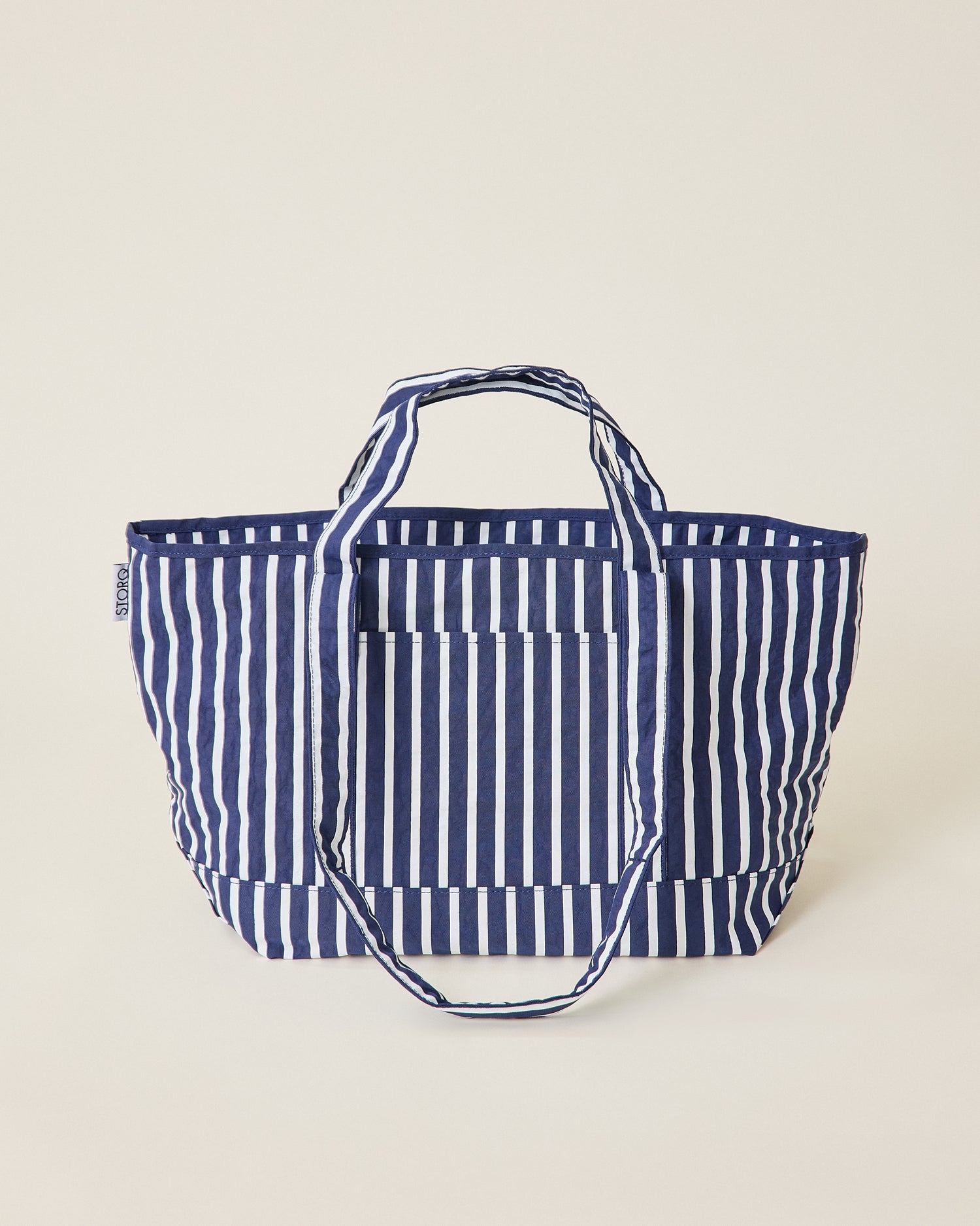 Navy blue and white striped Packable Park Carryall on a beige background