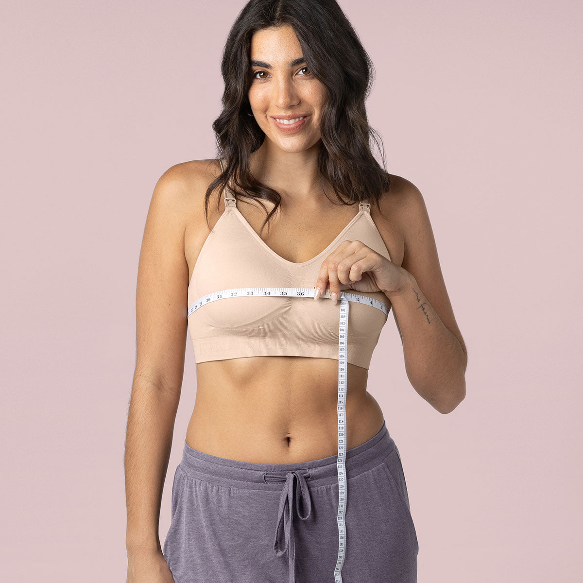 Model wearing the Simply Sublime Nursing Bra in Beige holding measuring tape around bust