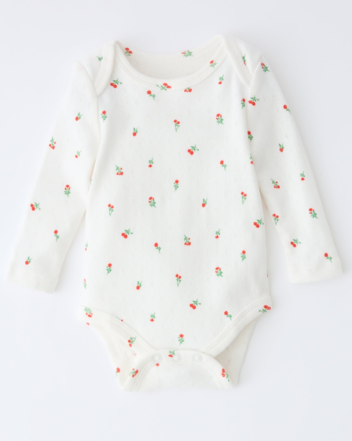Pointelle Long Sleeve Onesie in Dainty Ditsy pattern on a beige background.