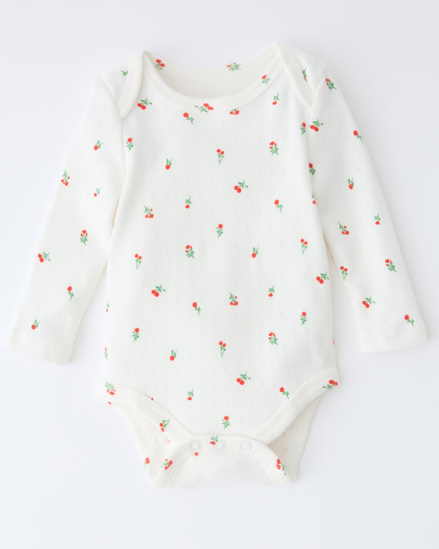 Pointelle Long Sleeve Onesie in Dainty Ditsy pattern on a beige background.