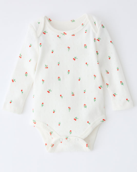 Pointelle Long Sleeve Onesie in Dainty Ditsy pattern on a beige background.