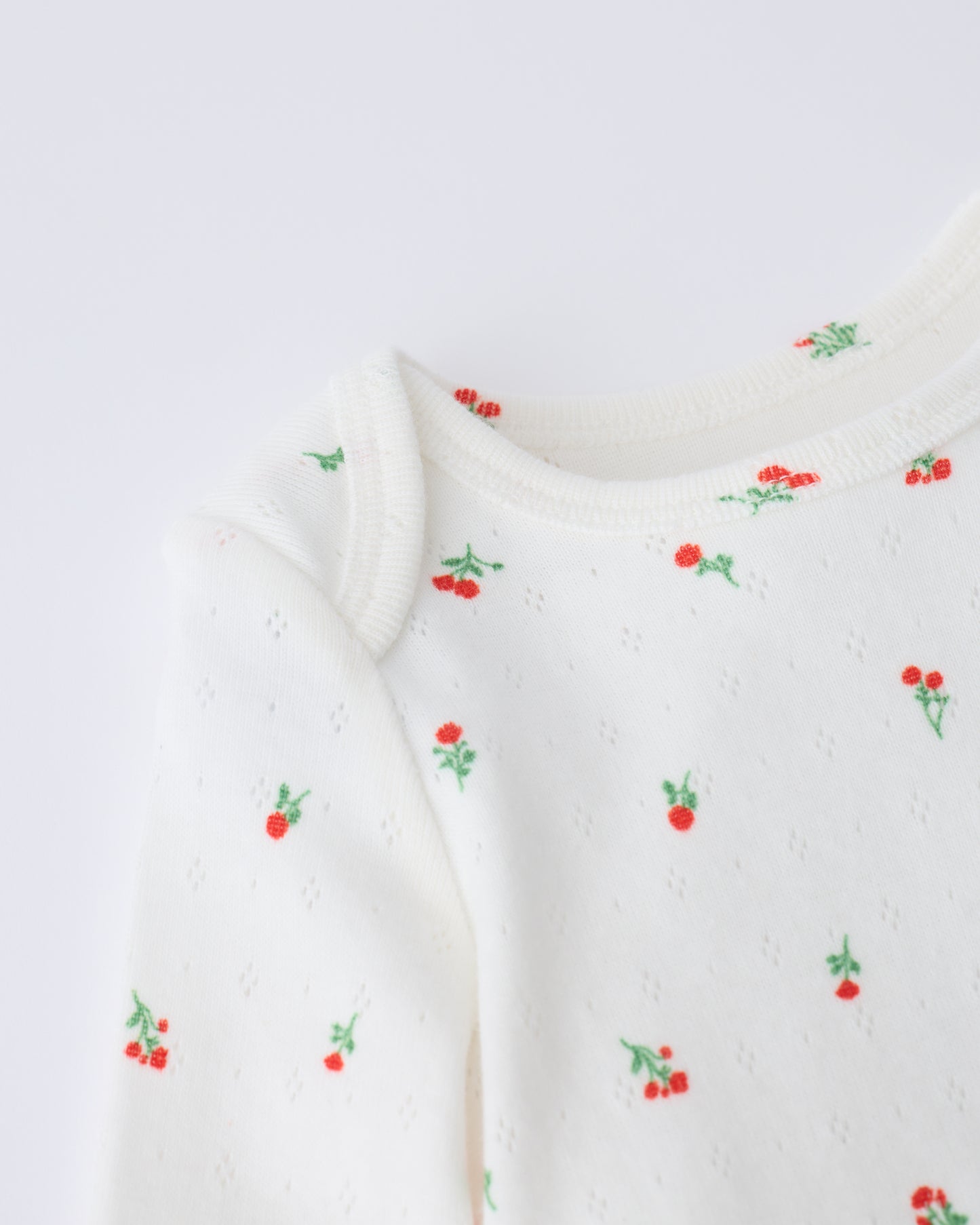 Close up of collar detail on the Pointelle Long Sleeve Onesie in Dainty Ditsy pattern on a beige background.