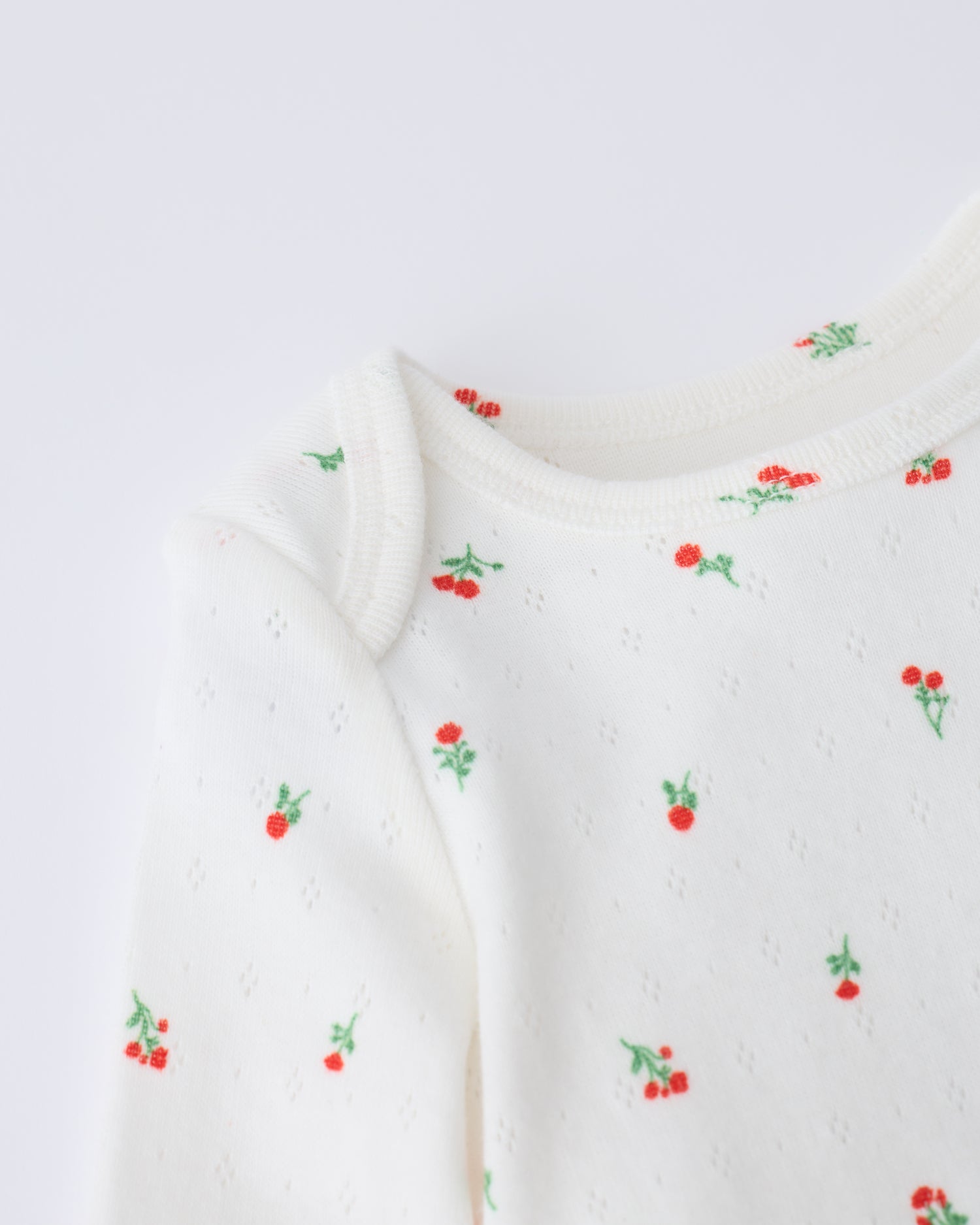 Close up of collar detail on the Pointelle Long Sleeve Onesie in Dainty Ditsy pattern on a beige background.